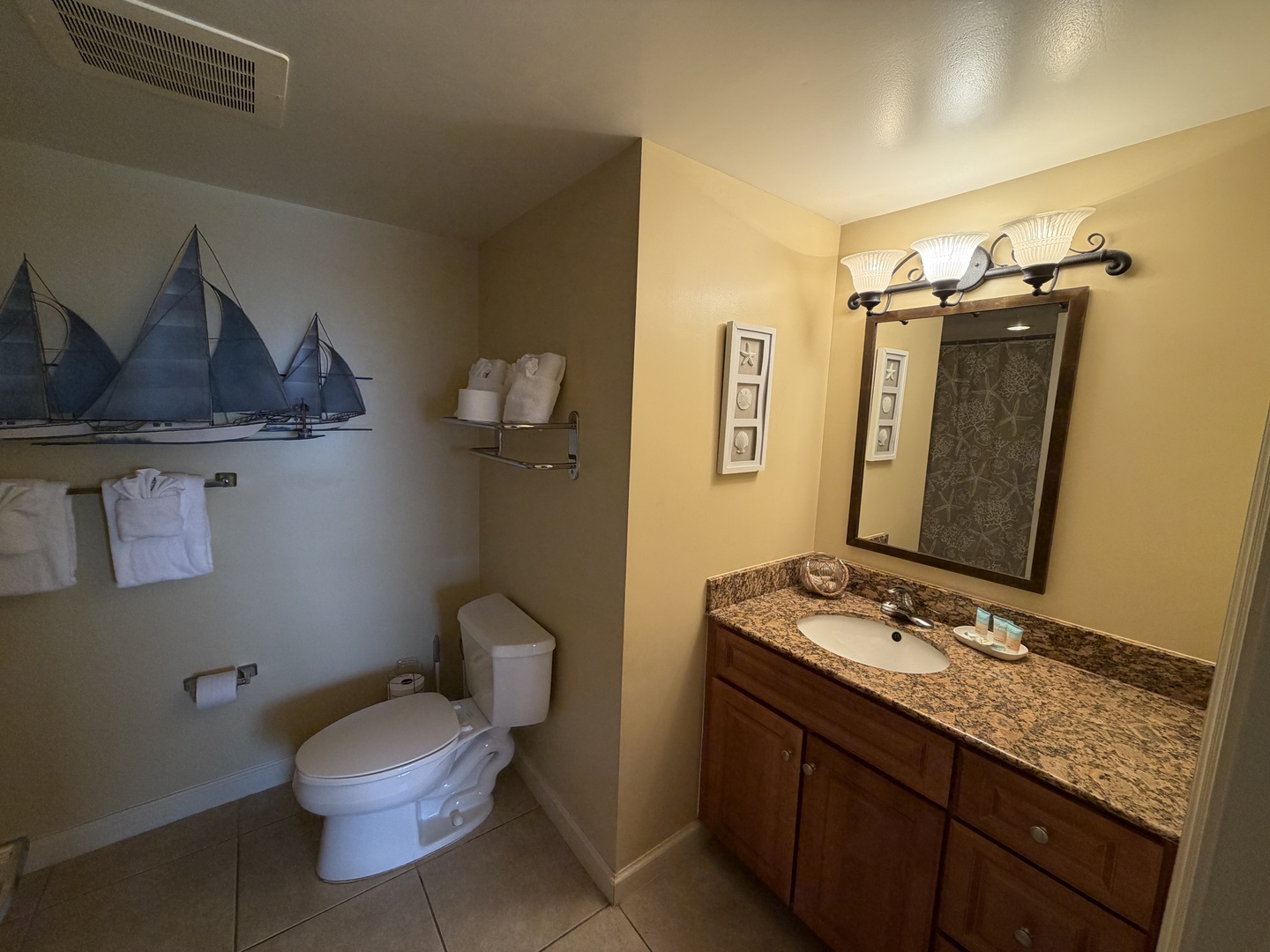 Your private bathroom features granite countertops, warm lighting, and nautical touches that create a serene coastal retreat.