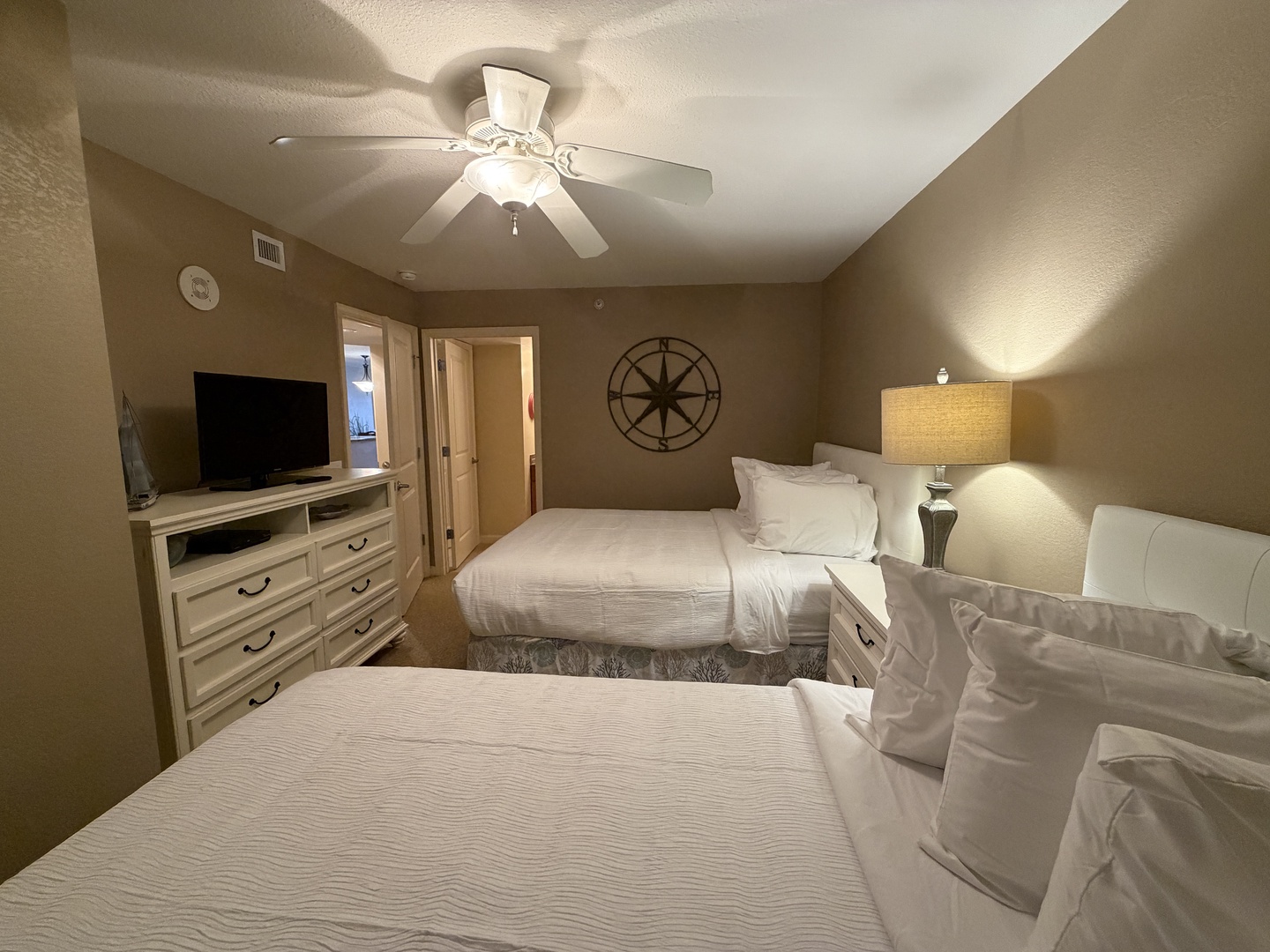 Rest peacefully in your cozy bedroom with two comfortable beds, ceiling fan, and nautical charm for a perfect night's sleep.