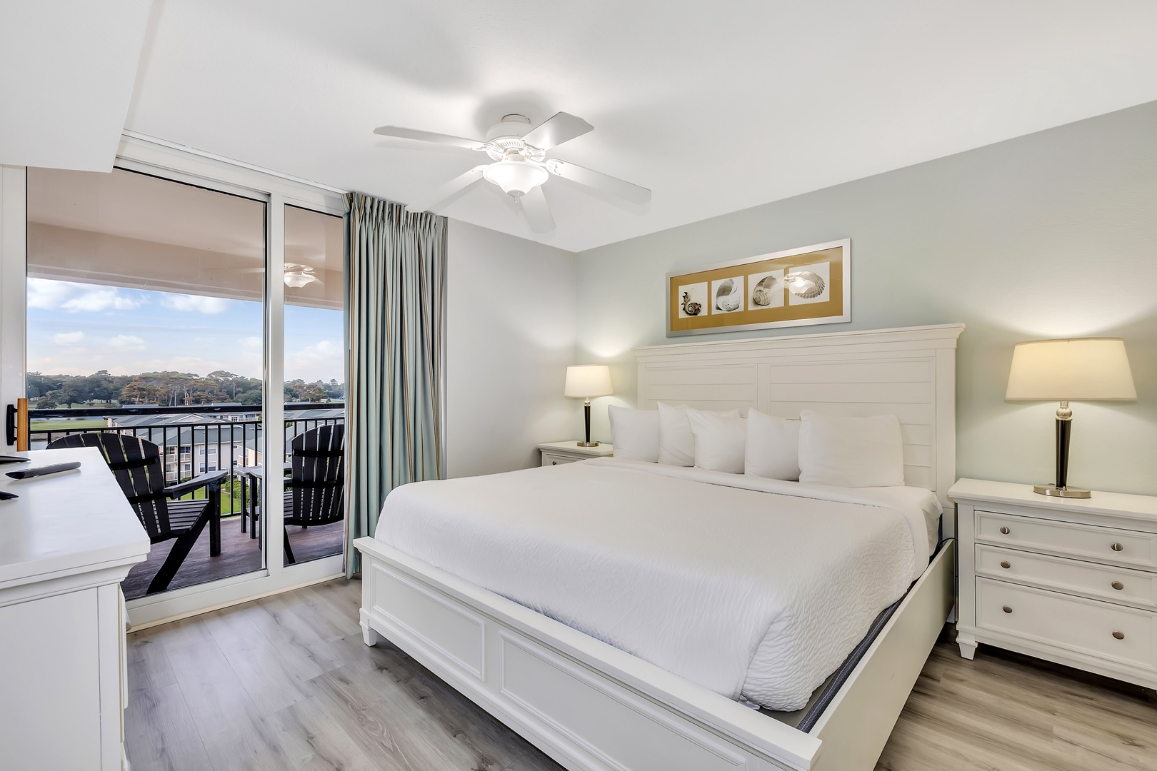 Step into this bright, serene bedroom where a plush bed, gentle ceiling fan, and waterfront balcony await. Picture waking to waterside views and stepping out to your private outdoor retreat.