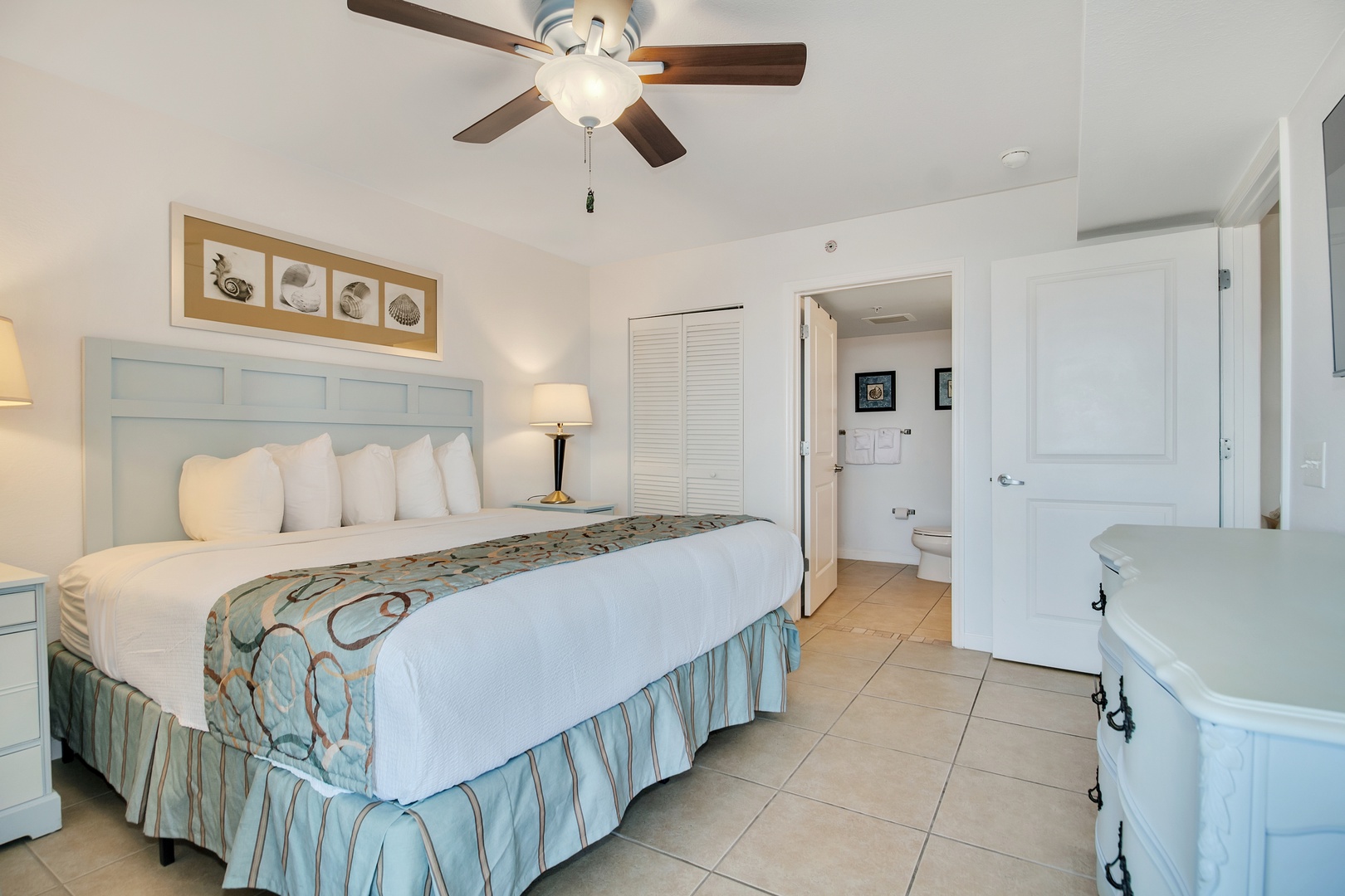 Relax in this bright, airy bedroom with ceiling fan, plush bedding, and coastal-inspired décor creating your perfect beach retreat.