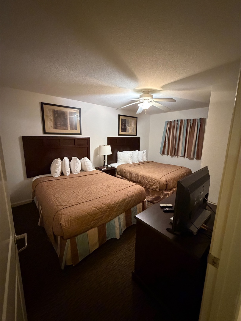 Your comfortable bedroom features two plush beds with fresh linens, a ceiling fan for your comfort, and thoughtful touches to help you unwind after a day of exploring.
