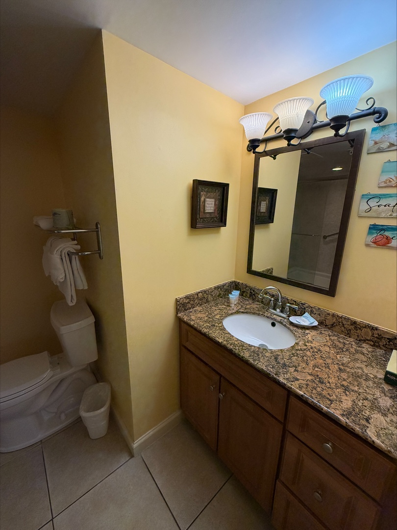 Your bathroom features a granite vanity, tiled shower, and cheerful coastal touches—bright, clean, and perfectly comfortable for your stay.