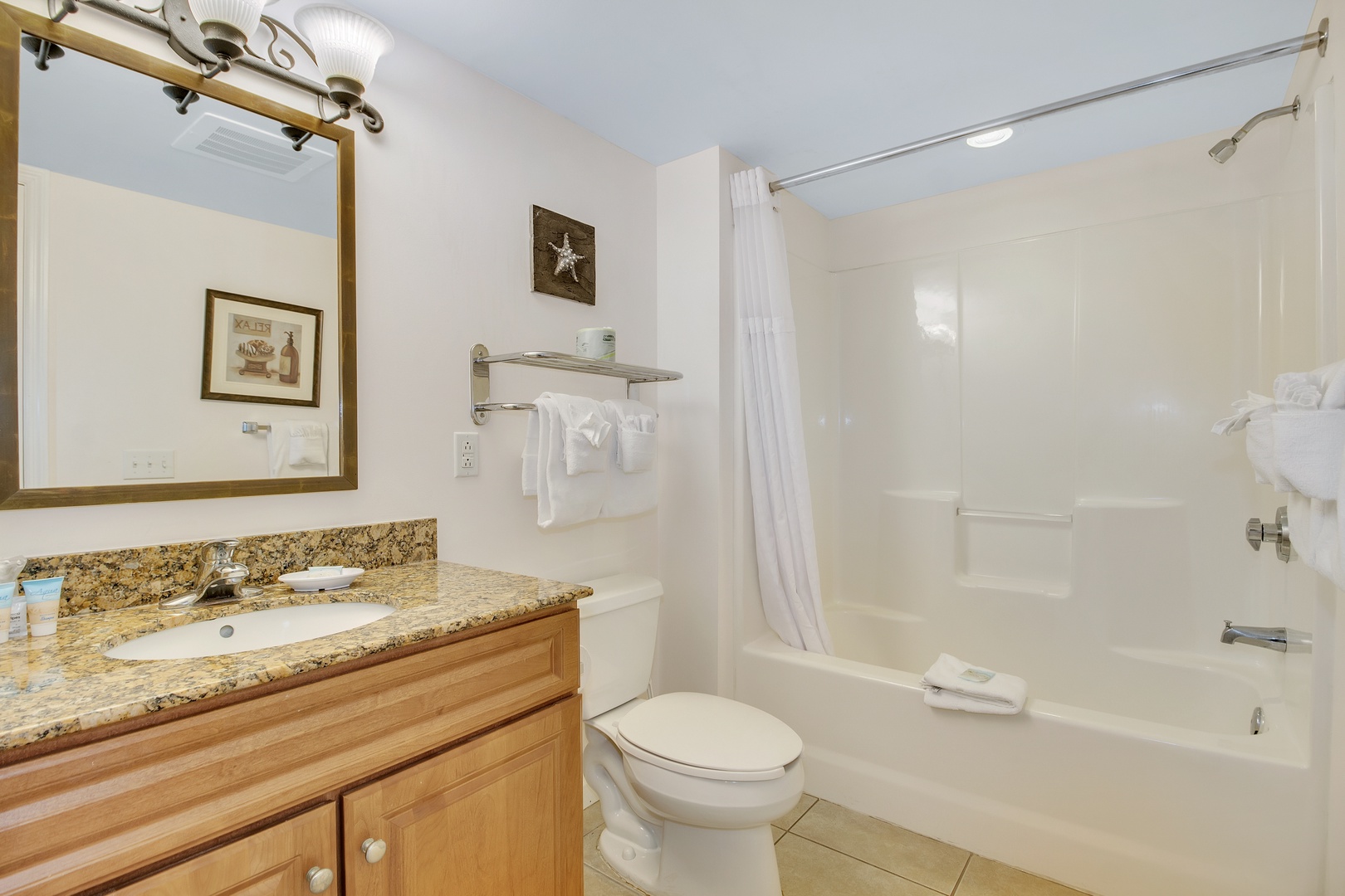 Refresh in your spacious bathroom with granite countertops, full tub-shower combo, and thoughtful touches like fresh towels and coastal decor.