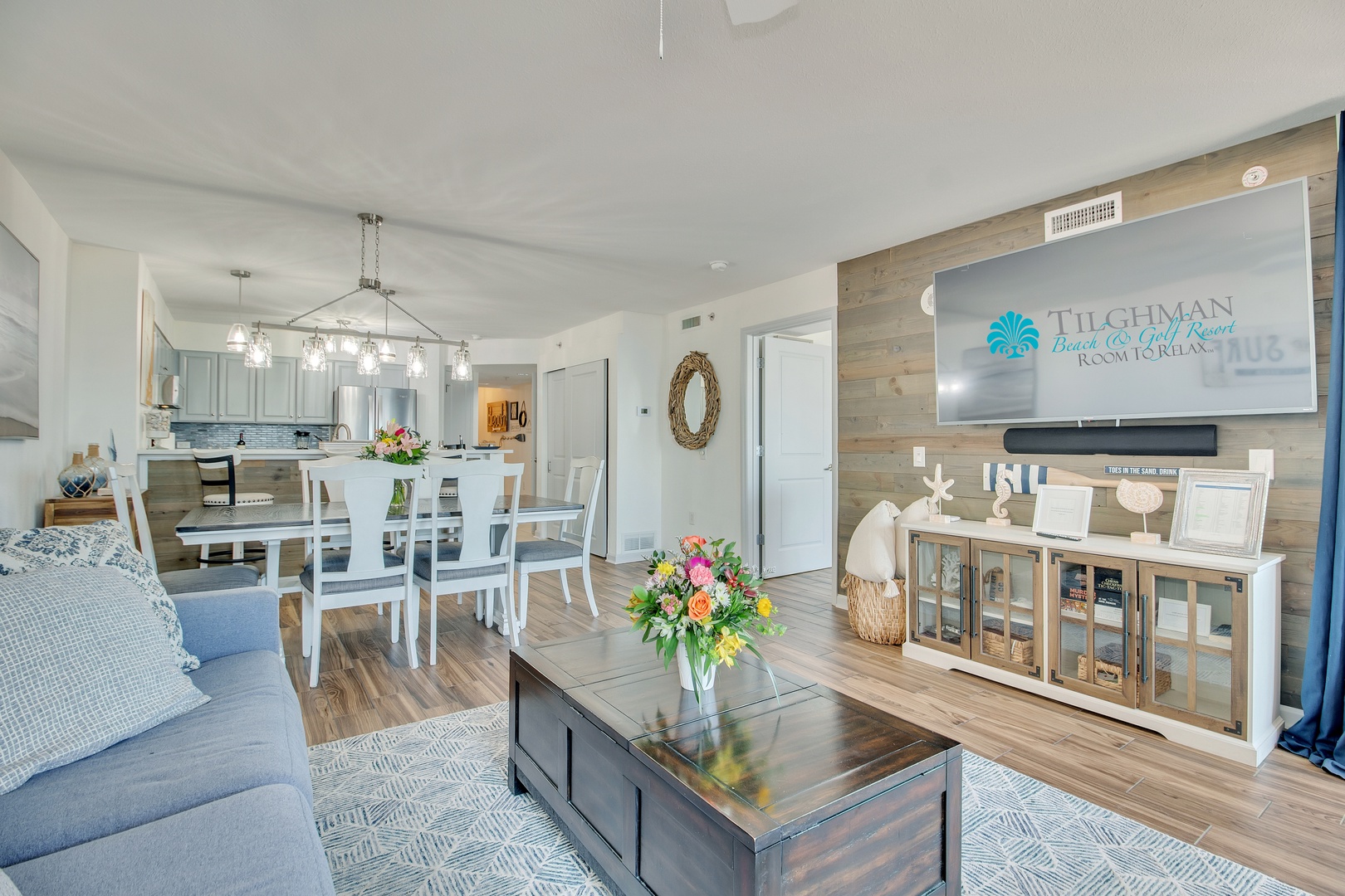 Relax in your beautifully appointed open-concept living space, where coastal charm meets modern comfort with fresh flowers and stylish furnishings.