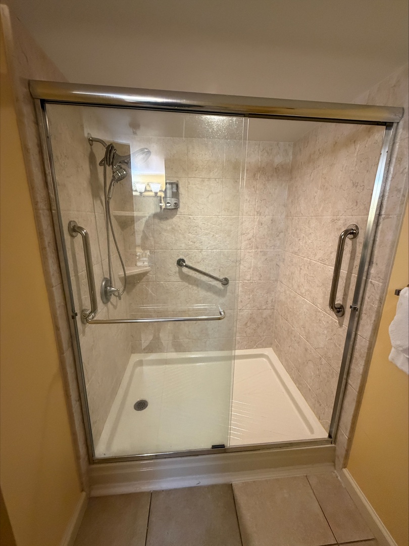 Step into your spacious walk-in shower with handheld and overhead fixtures, grab bars for safety, and a built-in shelf for your toiletries—designed for comfort and ease.
