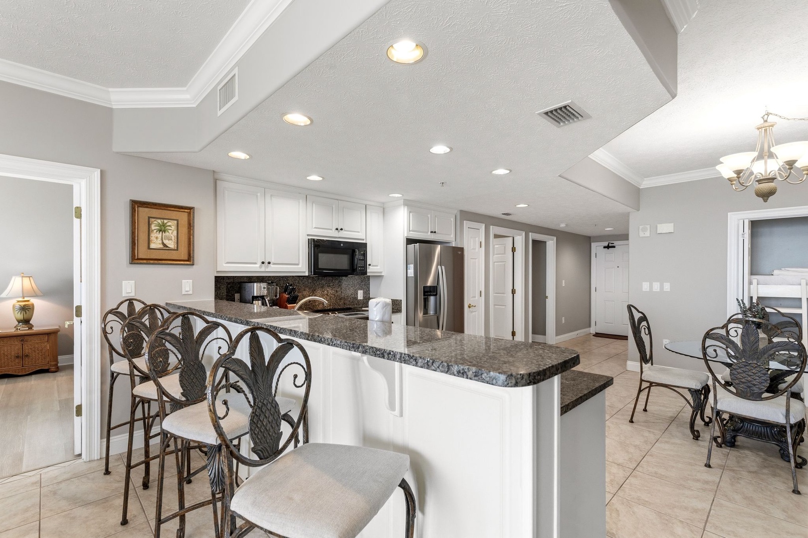 Your fully equipped kitchen features granite counters, modern appliances, and bar seating perfect for morning coffee or casual dining together.