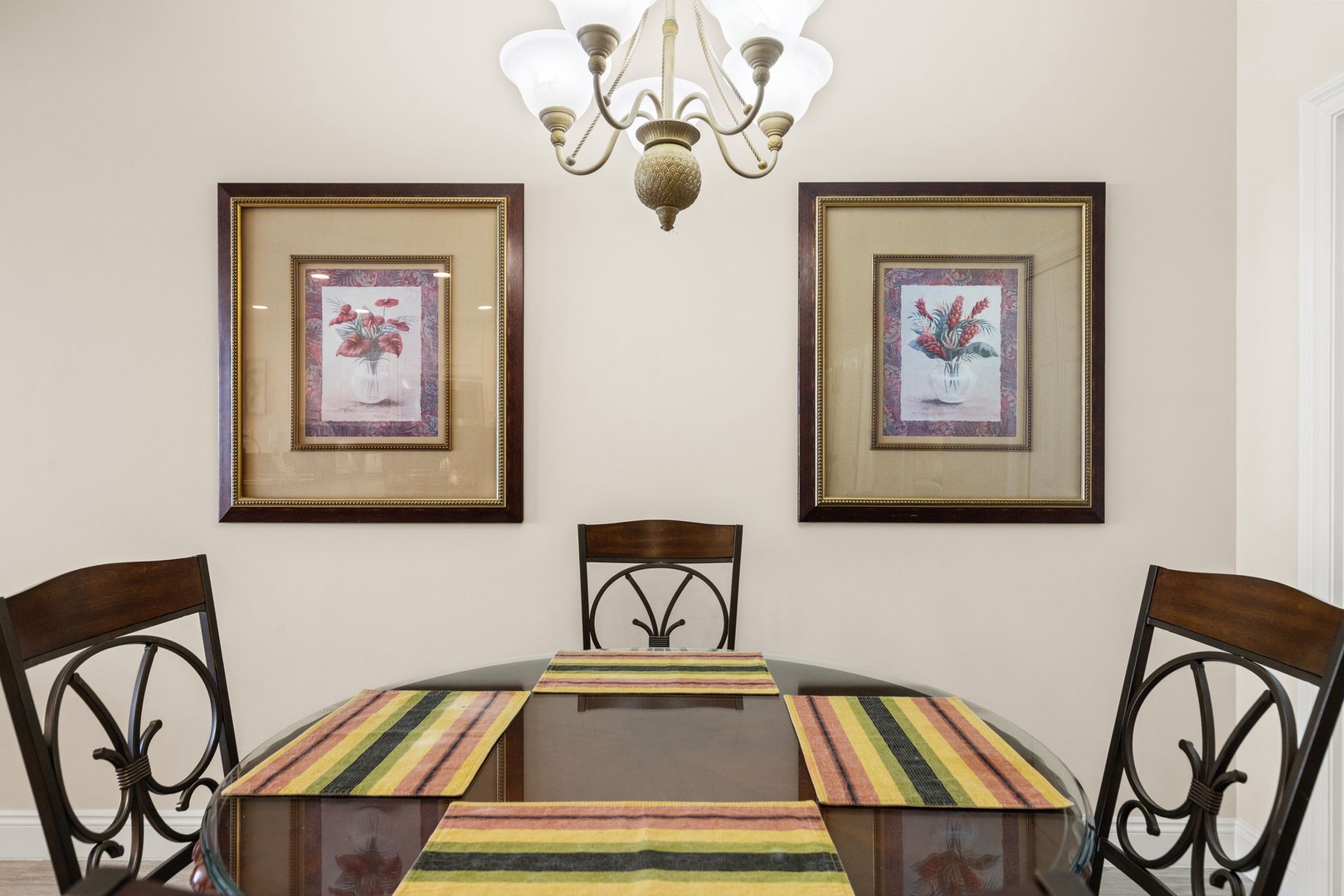 Gather around your elegant dining table where memorable meals unfold beneath warm chandelier light and charming botanical artwork.