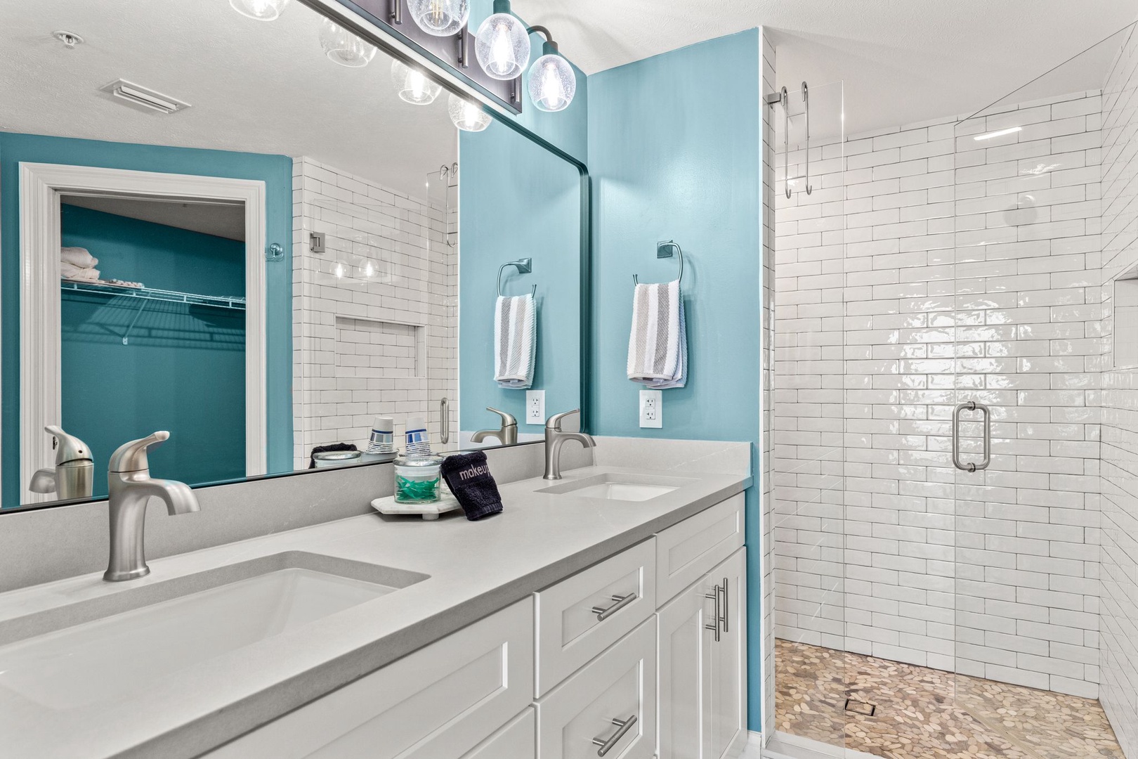Your private sanctuary features a dual-vanity design with elegant fixtures, a refreshing walk-in shower, and soft beach-inspired tones that invite relaxation.