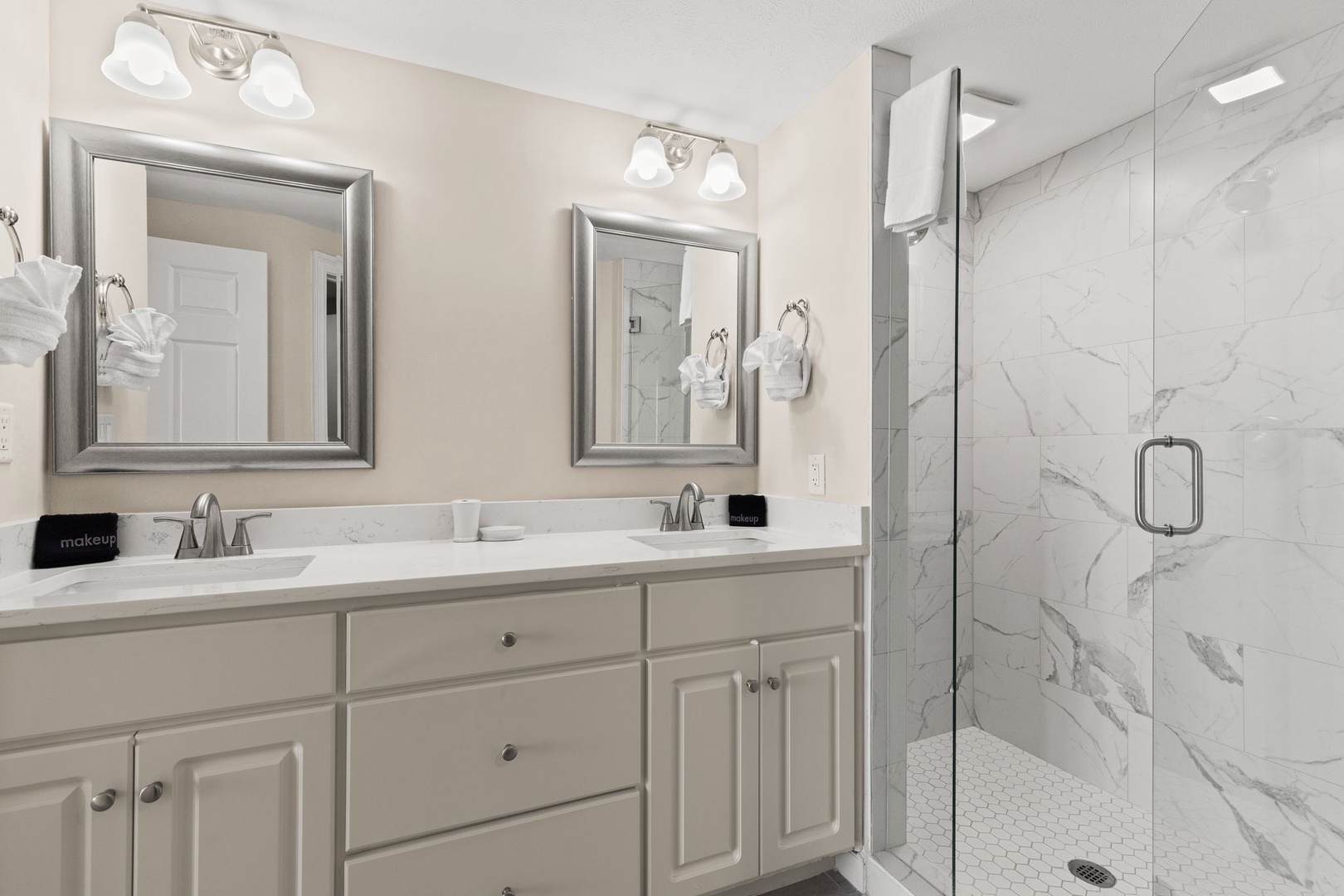 Step into your elegant marble-tiled bathroom with dual vanity and luxurious walk-in shower where fresh towels await your arrival.