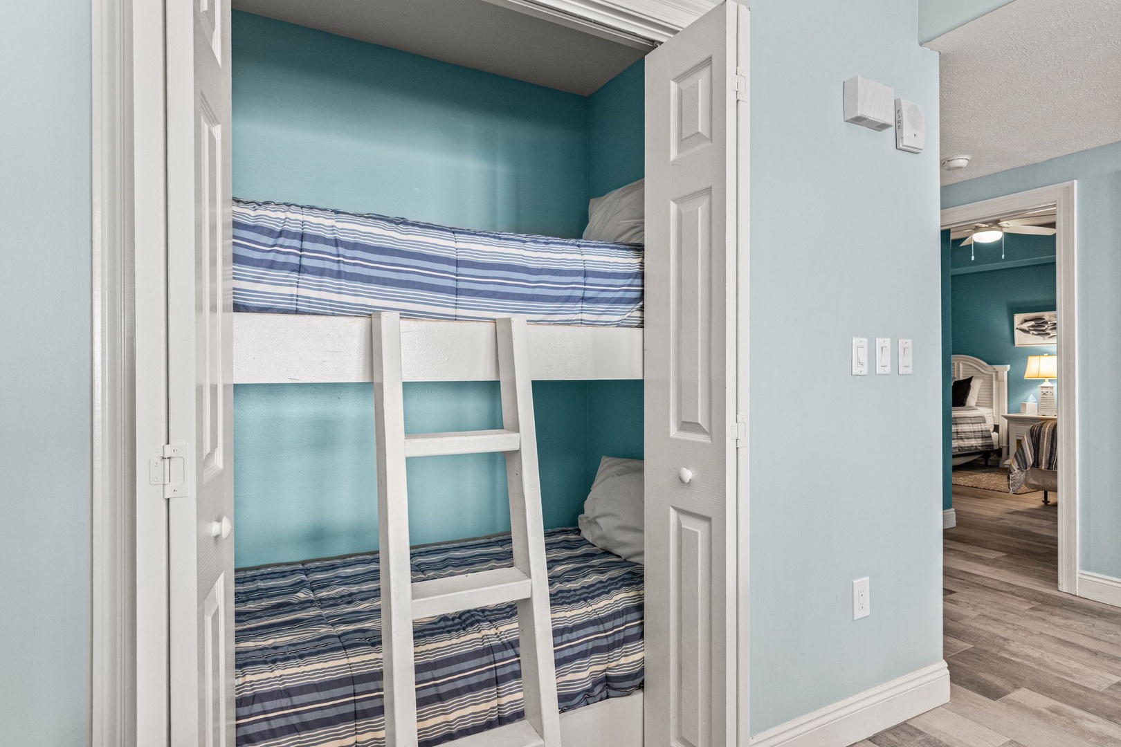 Your kids will love this cozy bunk nook with its calming coastal blue walls and crisp white ladder, perfect for bedtime stories and morning giggles.