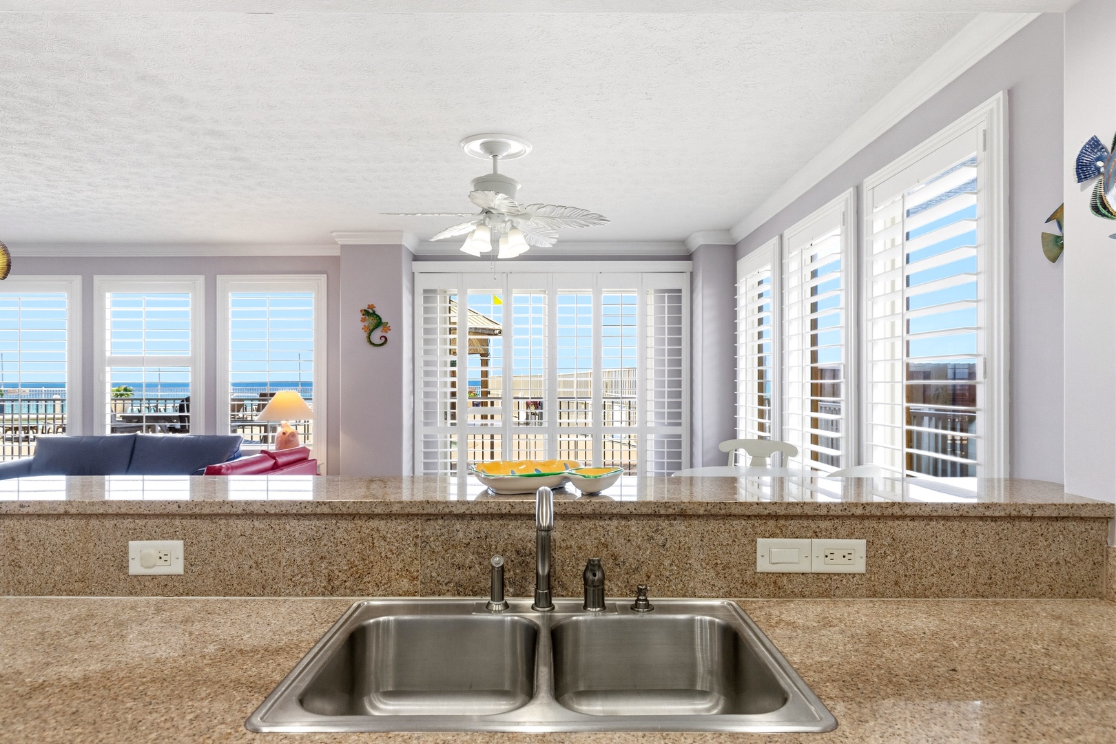 Your fully equipped kitchen opens to stunning ocean views through plantation shutters, creating the perfect backdrop for morning coffee or meal prep.