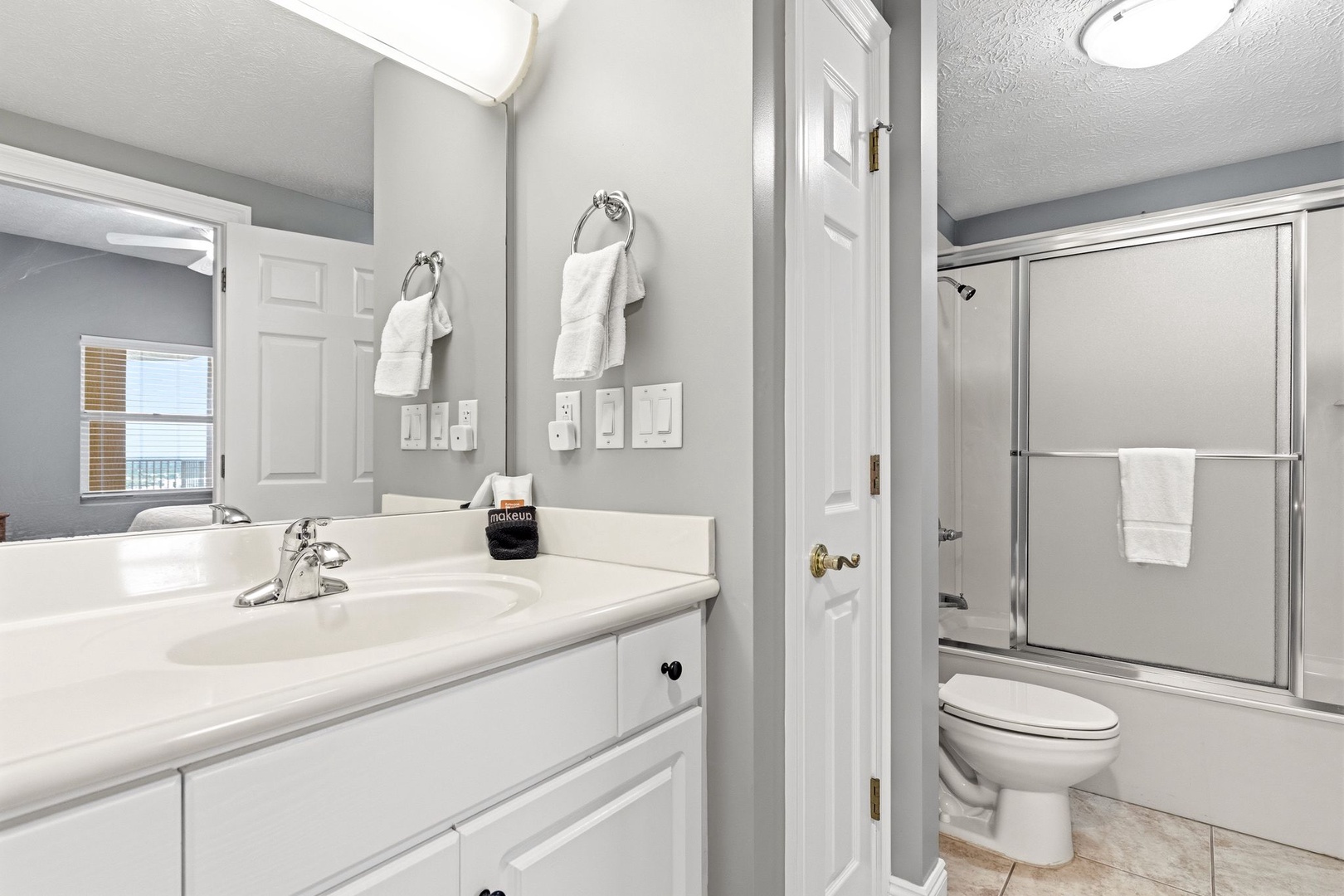Refresh in your spacious bathroom featuring dual vanities, pristine white cabinetry, and a convenient shower-tub combo.