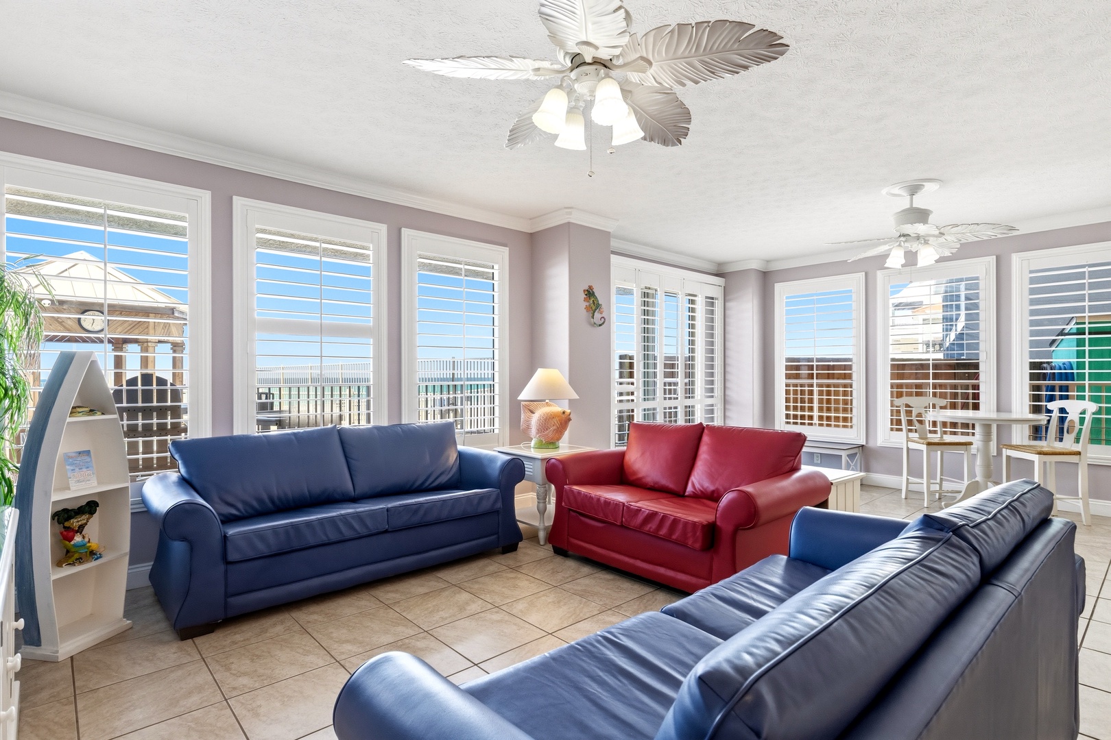Relax in your bright living room with colorful leather sofas and tropical ceiling fans while enjoying panoramic city views through floor-to-ceiling windows.