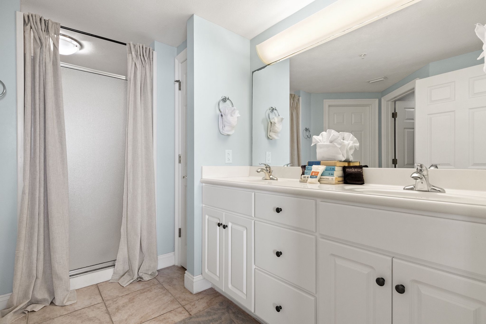 Step into your spacious, calming bathroom with soft blue walls, dual sinks, and ample counter space. Fresh towels await, and the walk-in shower offers a refreshing start to your day.