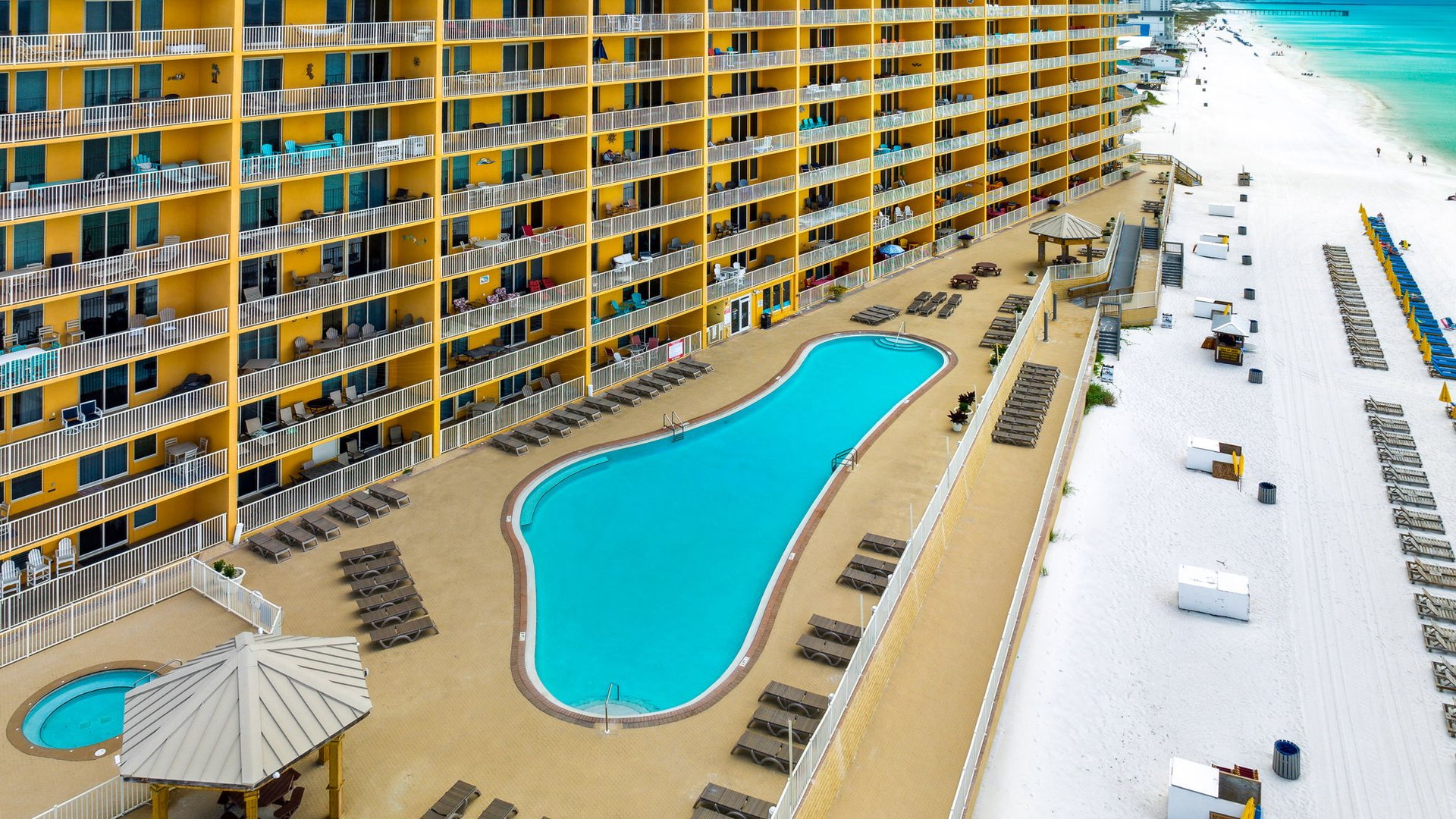 Aerial view of beachfront property featuring pools and direct beach access with crystal-clear waters.