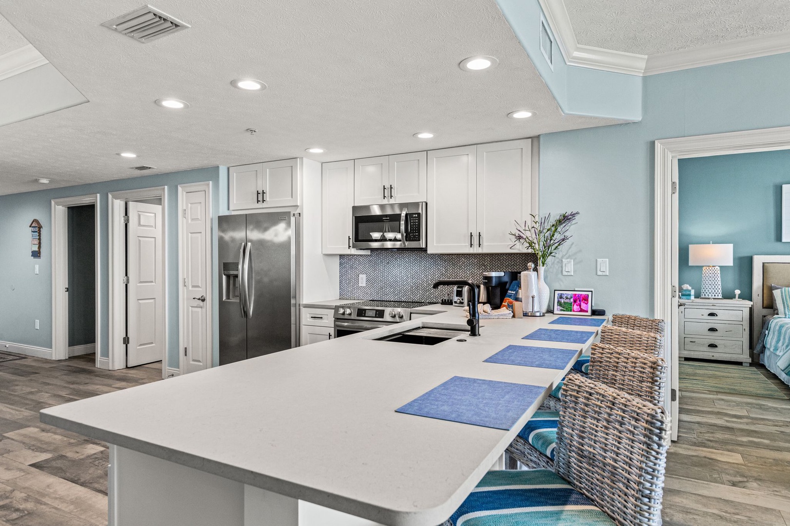 Your spacious kitchen boasts crisp white cabinetry, stainless steel appliances, and a generous island with bar seating—perfect for preparing vacation meals or enjoying morning coffee together.