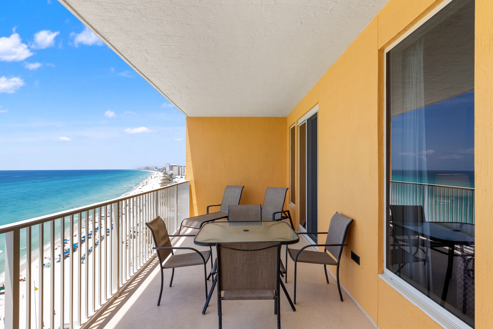 A spacious beachfront balcony with sweeping views of the turquoise Gulf and sandy shoreline, featuring outdoor dining for six plus lounge chairs for soaking up the sun.