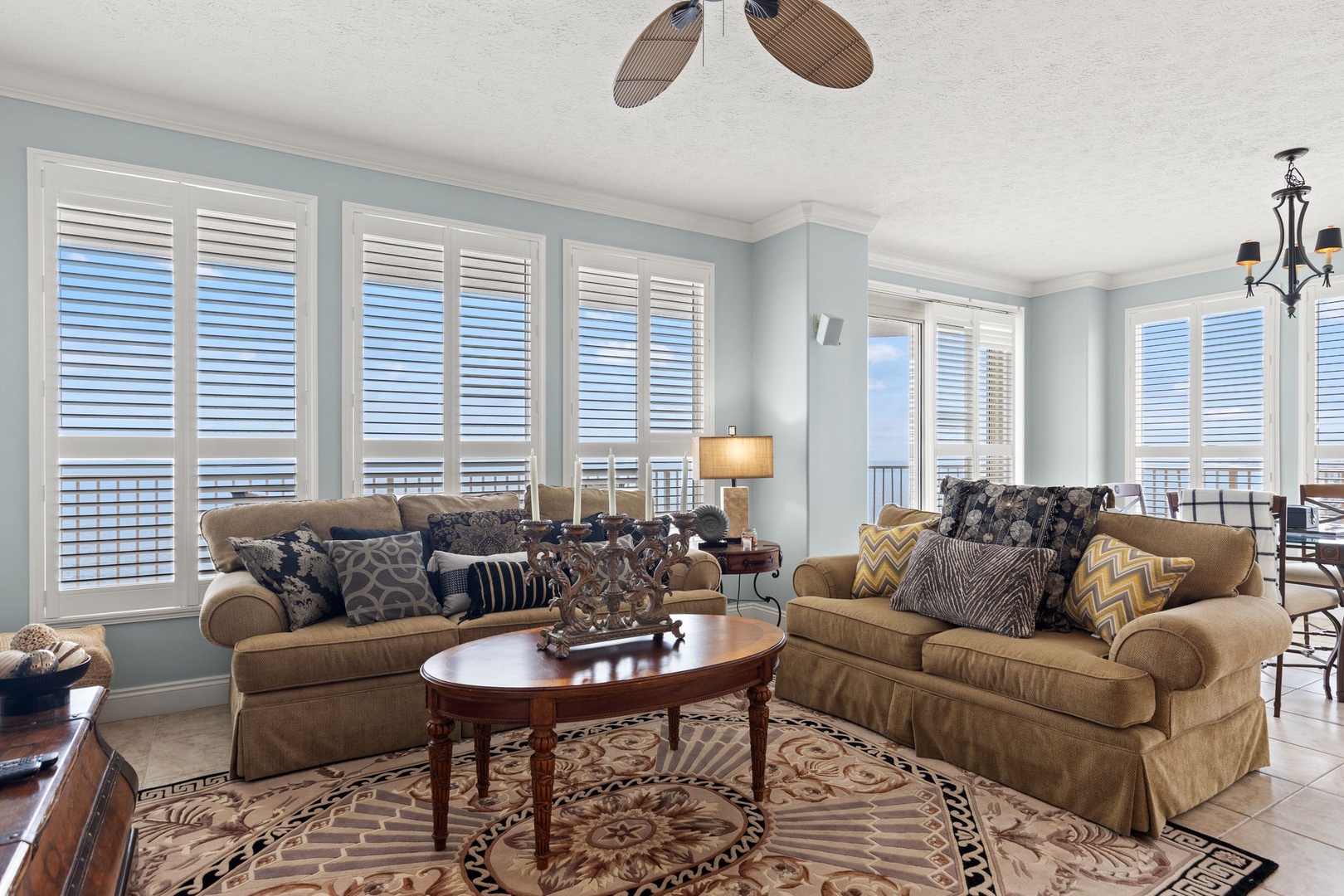 Unwind in your airy living room with plush sofas, tasteful accents, and plantation shutters framing ocean views—your perfect coastal retreat awaits.