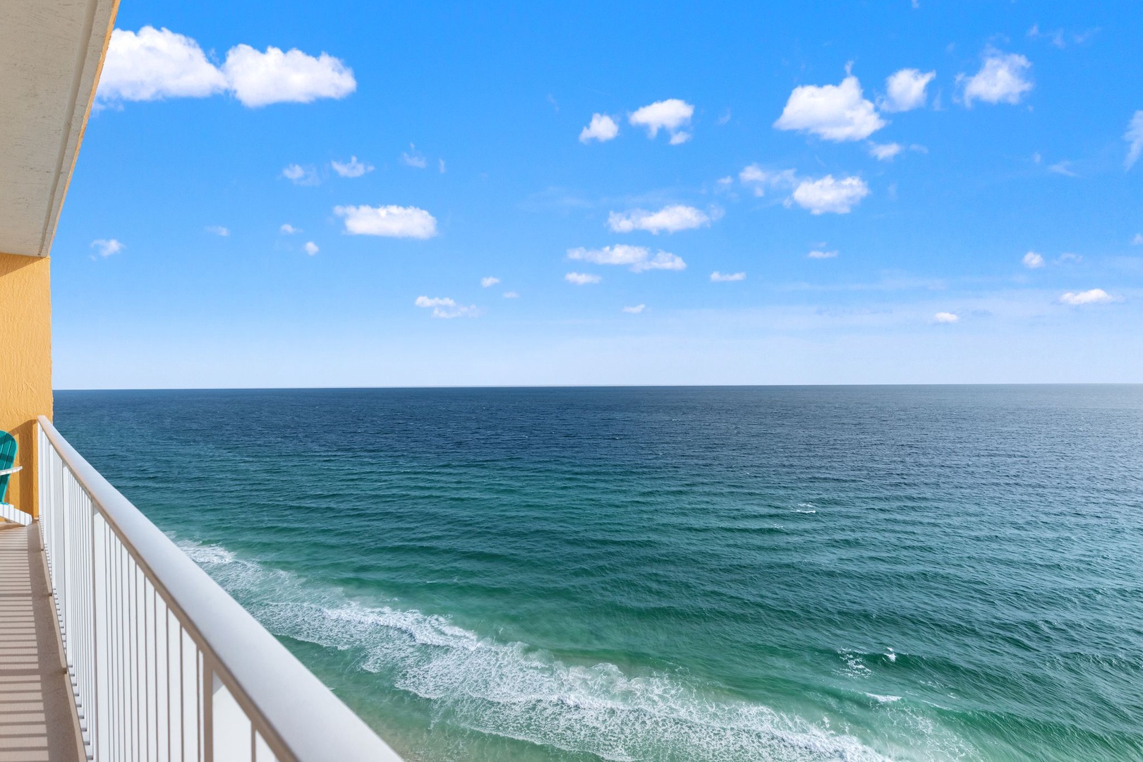 Stunning panoramic oceanfront view from private balcony showcasing turquoise waters meeting endless blue skies with gentle waves rolling toward shore.