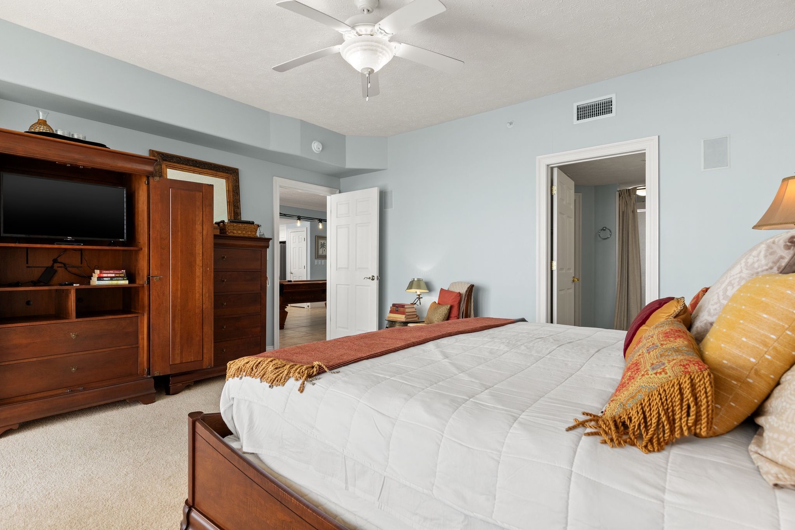 Drift off in your serene bedroom, where soft blue walls and a ceiling fan create a restful haven. Warm wood furnishings add character, while the ensuite bathroom is just steps away.