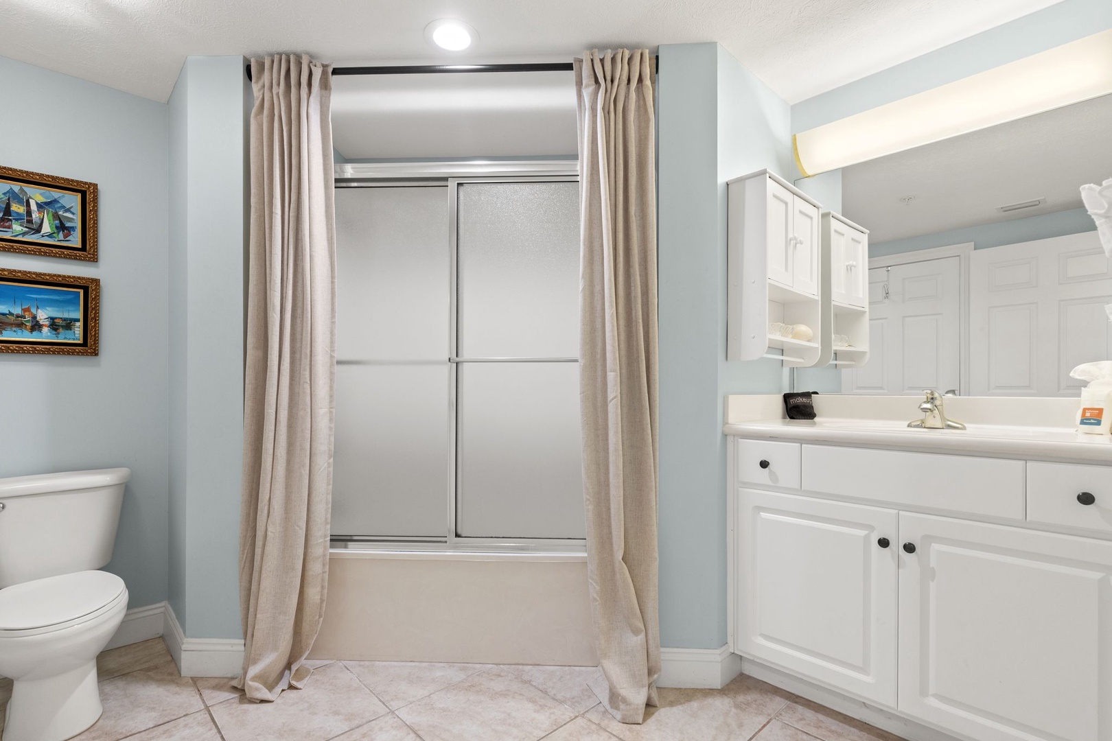 Refresh in this serene bathroom with its soothing blue tones, modern shower-tub combo, and crisp white cabinetry. Your clean, comfortable space awaits after a day of adventure.