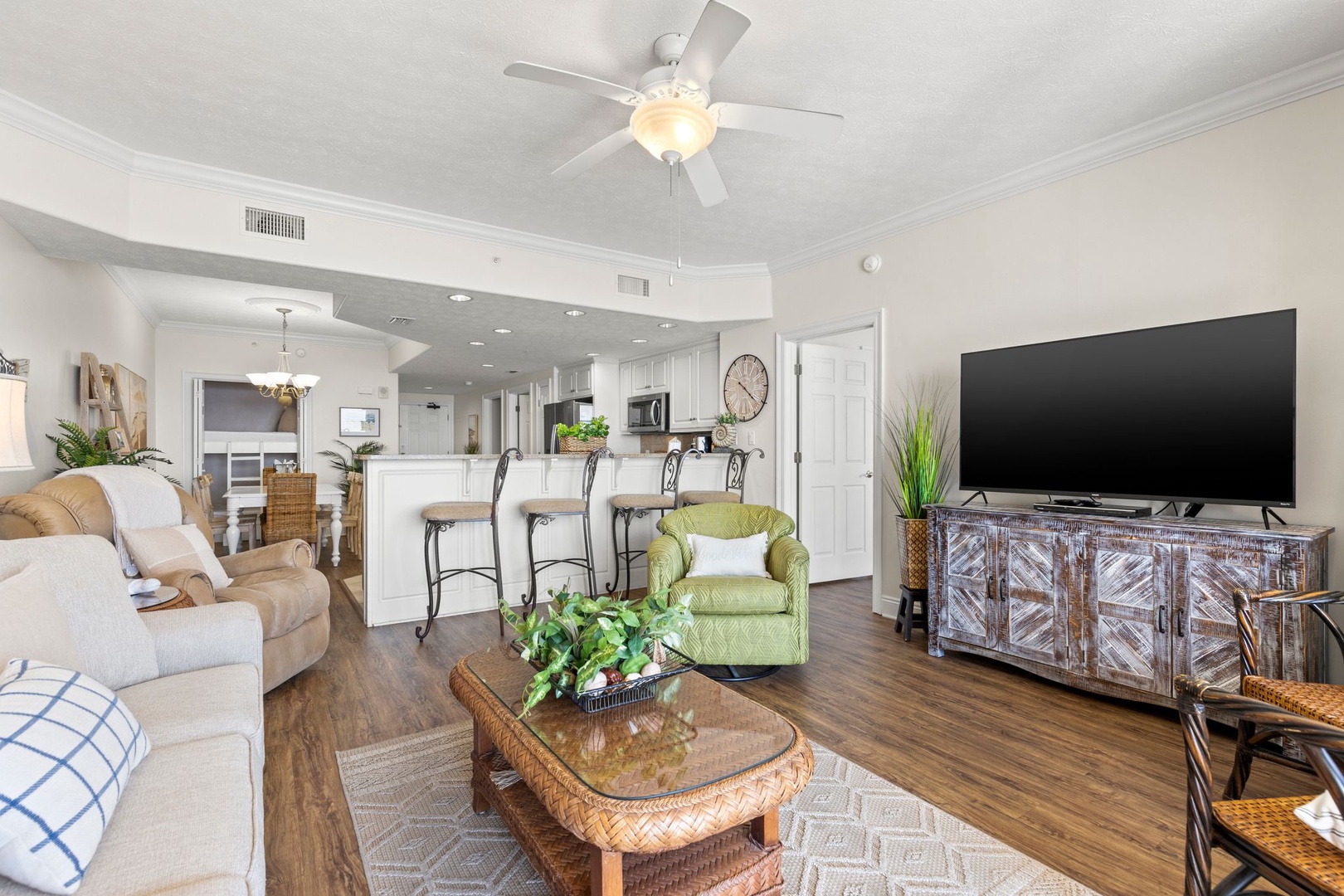 Picture yourself unwinding in this bright, open-concept retreat. Ceiling fan overhead, plush seating invites you to relax, while your open kitchen awaits. Coastal charm meets modern comfort—your perfect escape.