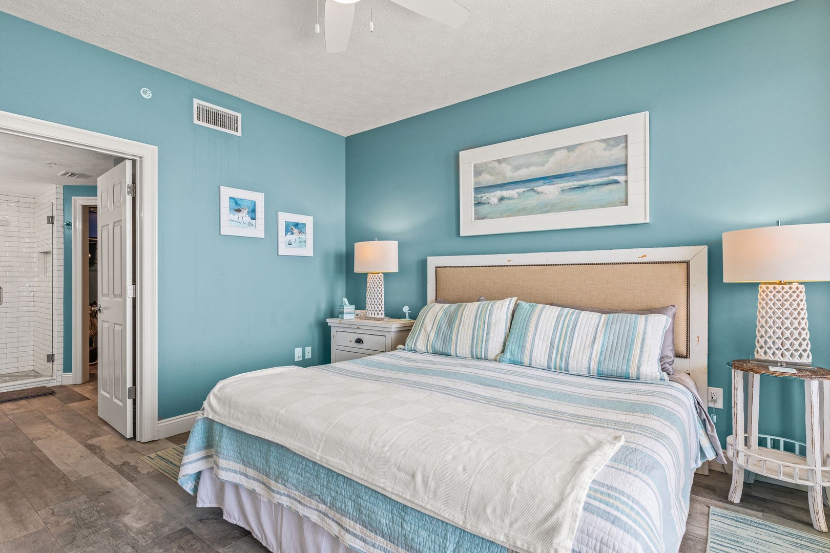 Sink into soft linens and coastal serenity in your private bedroom retreat. Soothing aqua walls and beach-inspired art create the perfect space to unwind after sun-soaked days.