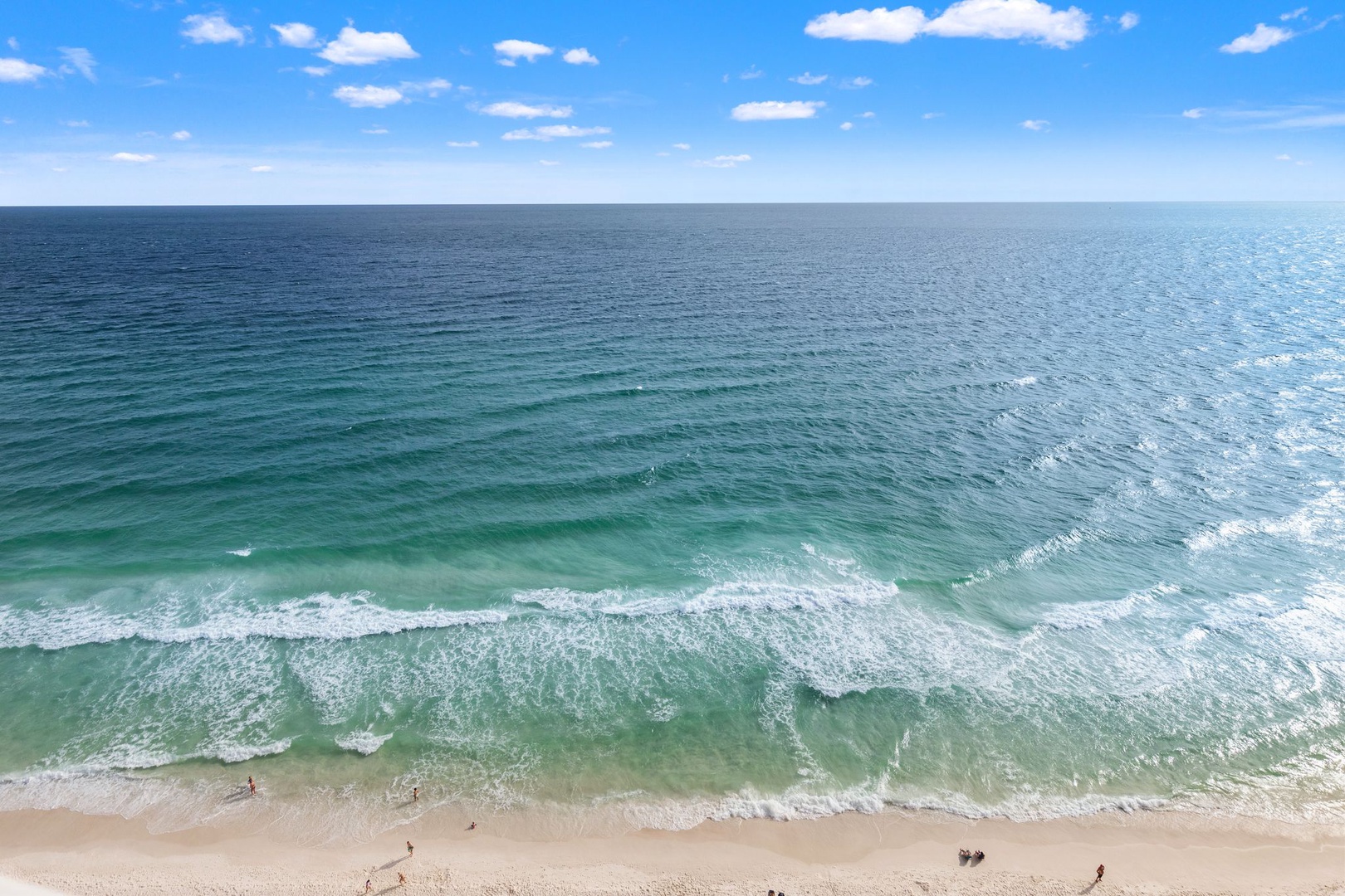 Aerial view captures pristine turquoise waters meeting white sand beach, showcasing the property's stunning coastal location and nearby recreation area.