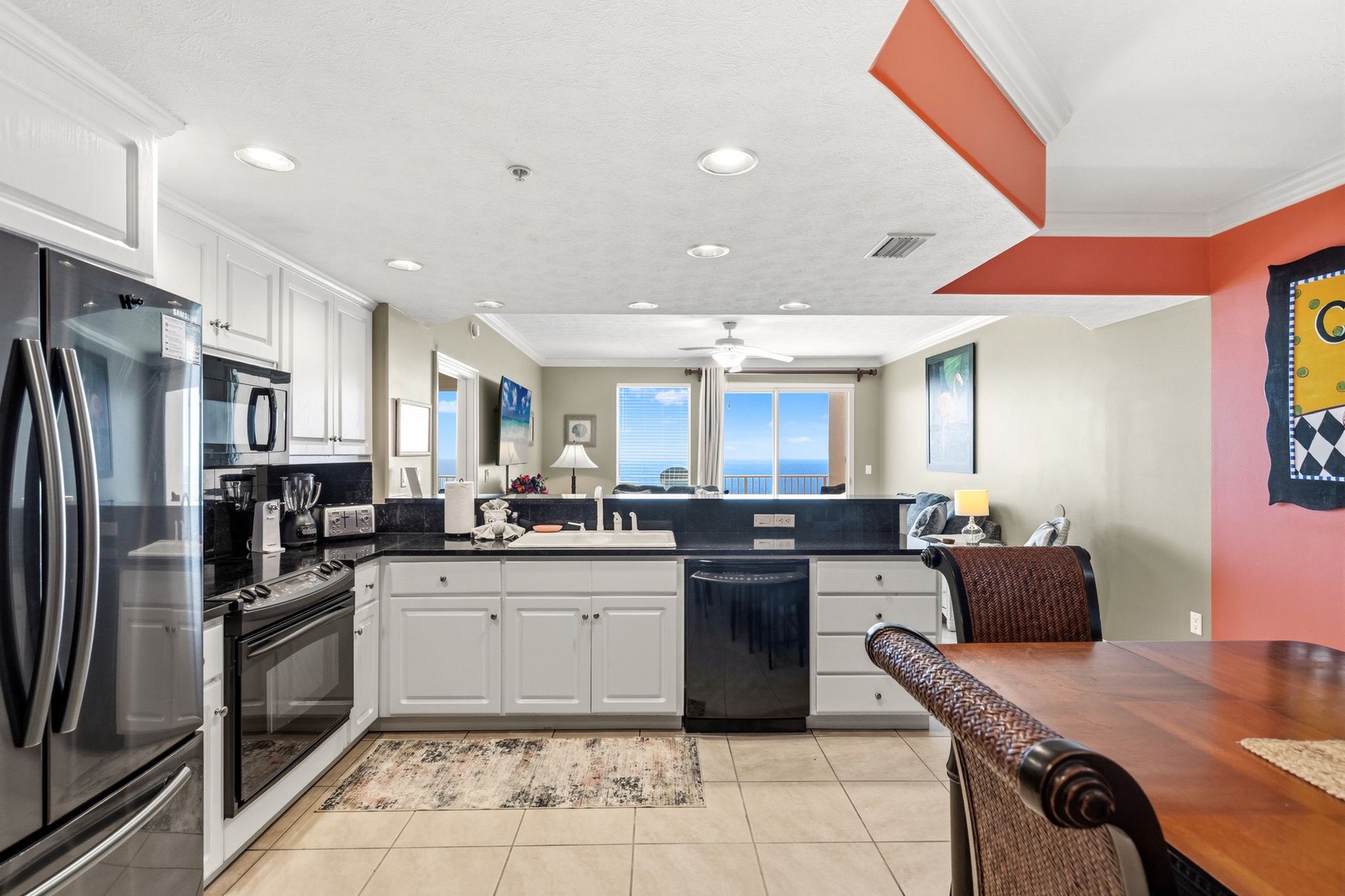 Your open kitchen flows seamlessly into the dining area, featuring modern appliances and stunning ocean views through large windows.