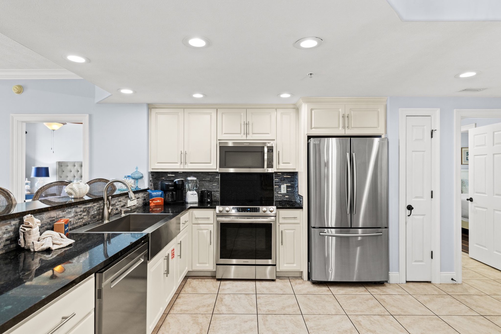Your fully equipped kitchen features stainless steel appliances, granite countertops, and sleek white cabinetry—perfect for preparing family meals or morning coffee during your stay.