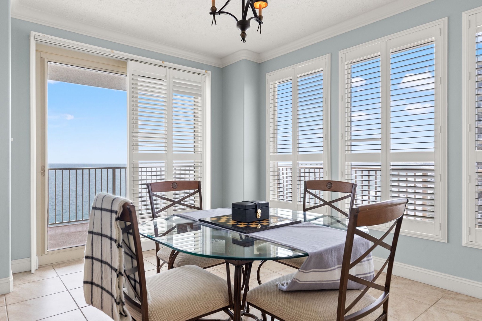 Picture yourself enjoying meals at this elegant glass-top table while soaking in the breathtaking ocean views through the shuttered windows. The coastal breeze beckons from your private balcony.