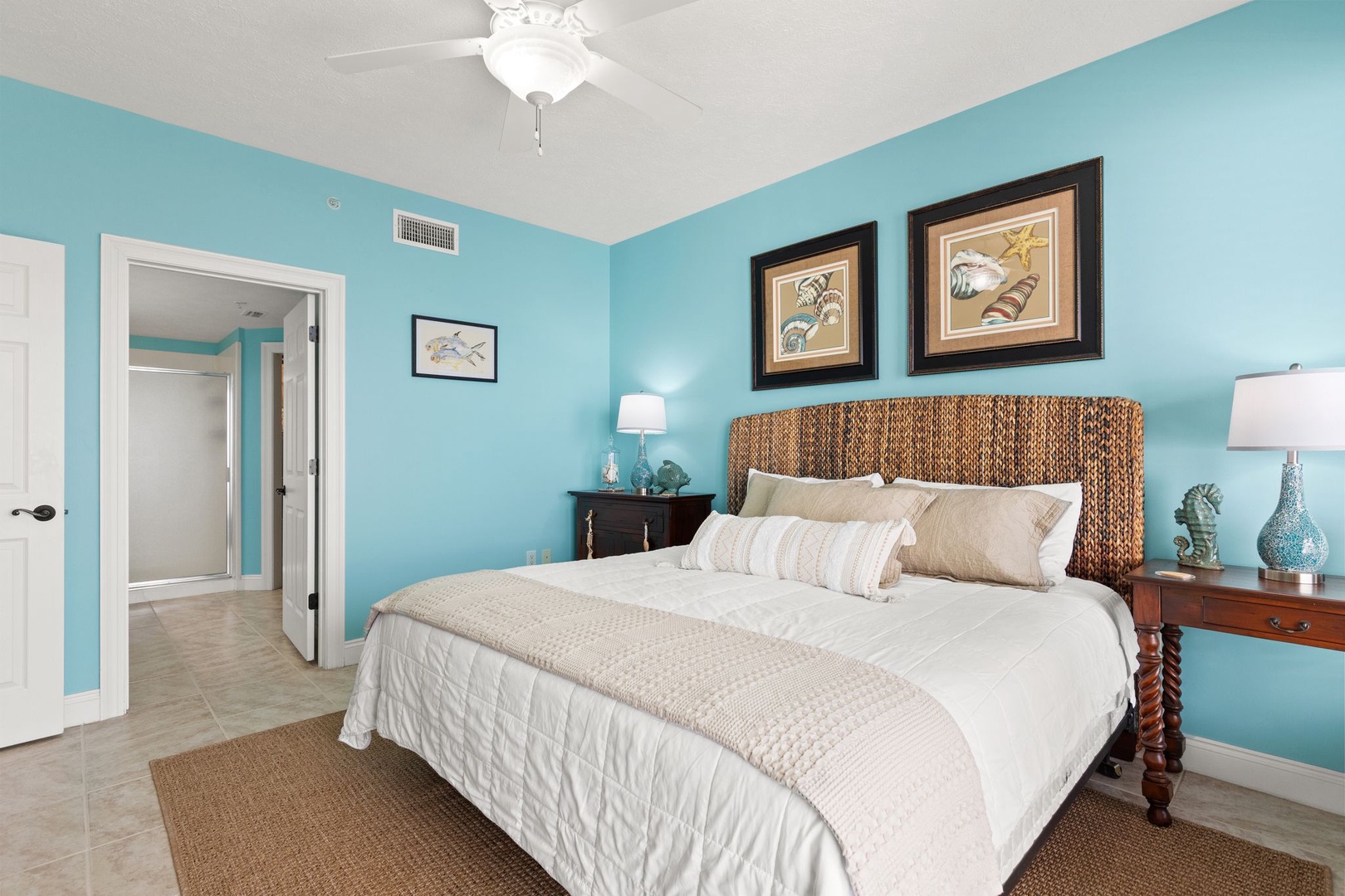 Drift off in your coastal-inspired bedroom with soft aqua walls, a woven headboard, and beach-themed art setting a soothing, seaside tone.