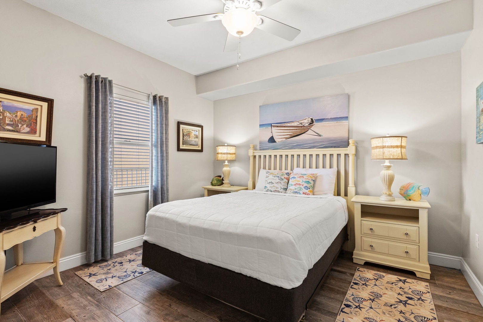 Slip into crisp linens and let the coastal artwork transport you to peaceful shores, with a ceiling fan keeping your evenings cool and comfortable.
