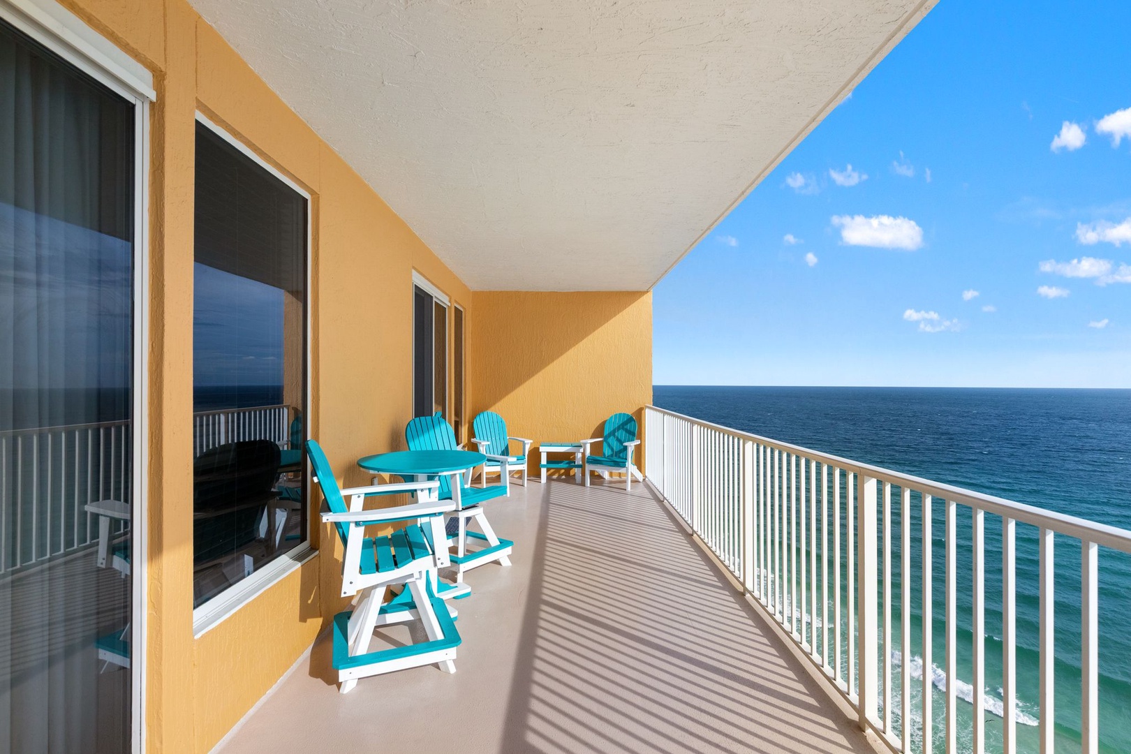 Your private balcony with turquoise coastal chairs invites you to sip morning coffee while soaking in endless ocean views and salty breezes.