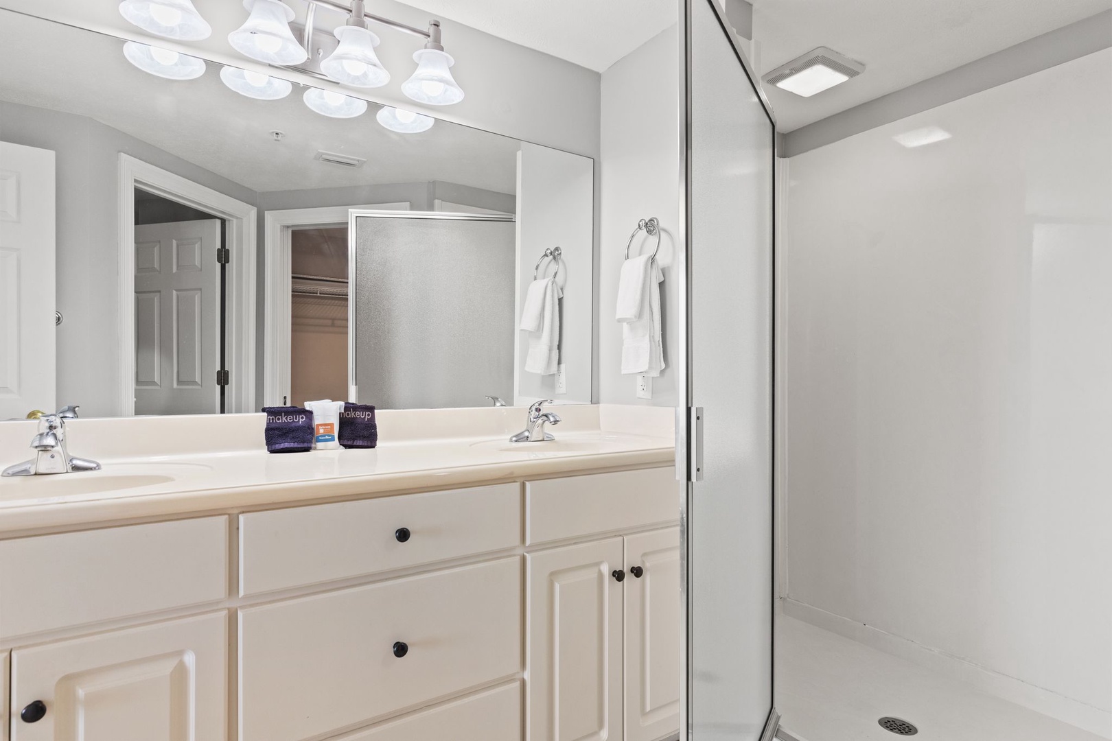 Your private bathroom features dual sinks, bright vanity lighting, and a spacious walk-in shower—perfect for refreshing after a day of exploring.