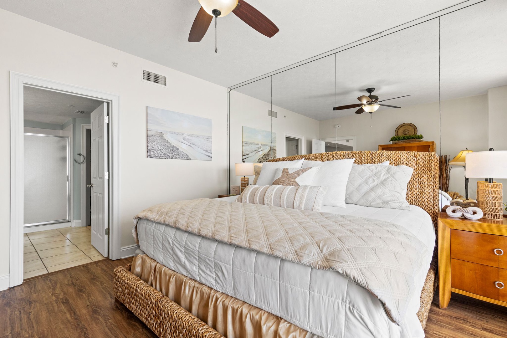 Sink into the plush linens and coastal textures of your serene bedroom retreat, where ceiling fans and natural light create your perfect sanctuary.