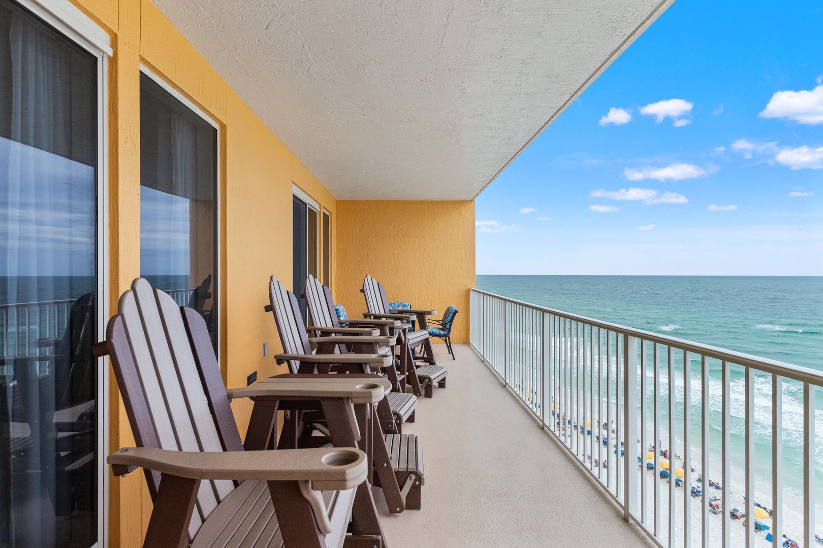 Spacious oceanfront balcony with Adirondack chairs overlooking turquoise waters and sandy shores, perfect for your morning coffee or sunset unwind.