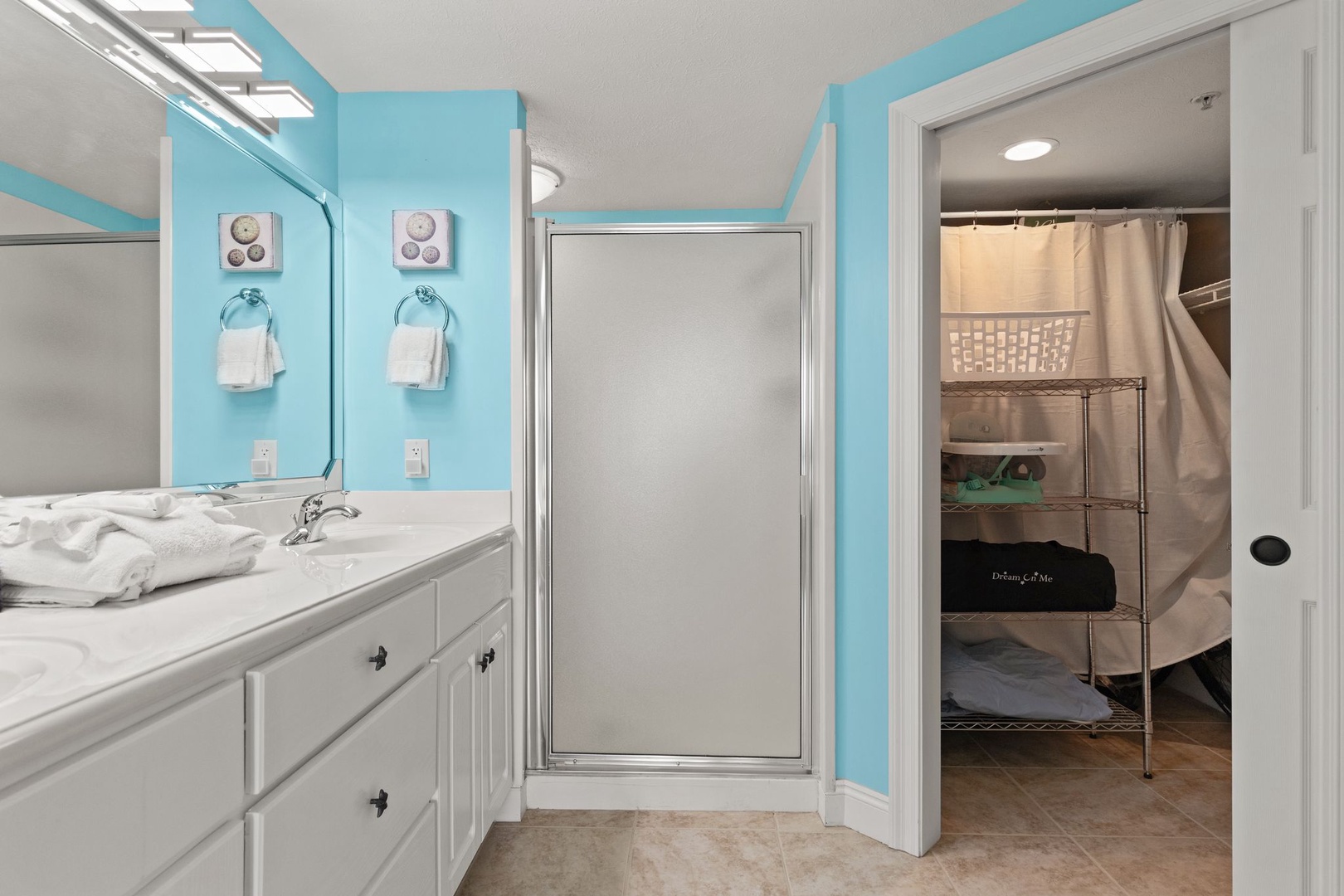 Bright, cheerful bathroom with coastal aqua walls, dual vanities, and walk-in shower—your refreshing retreat after a day of sun and adventure.