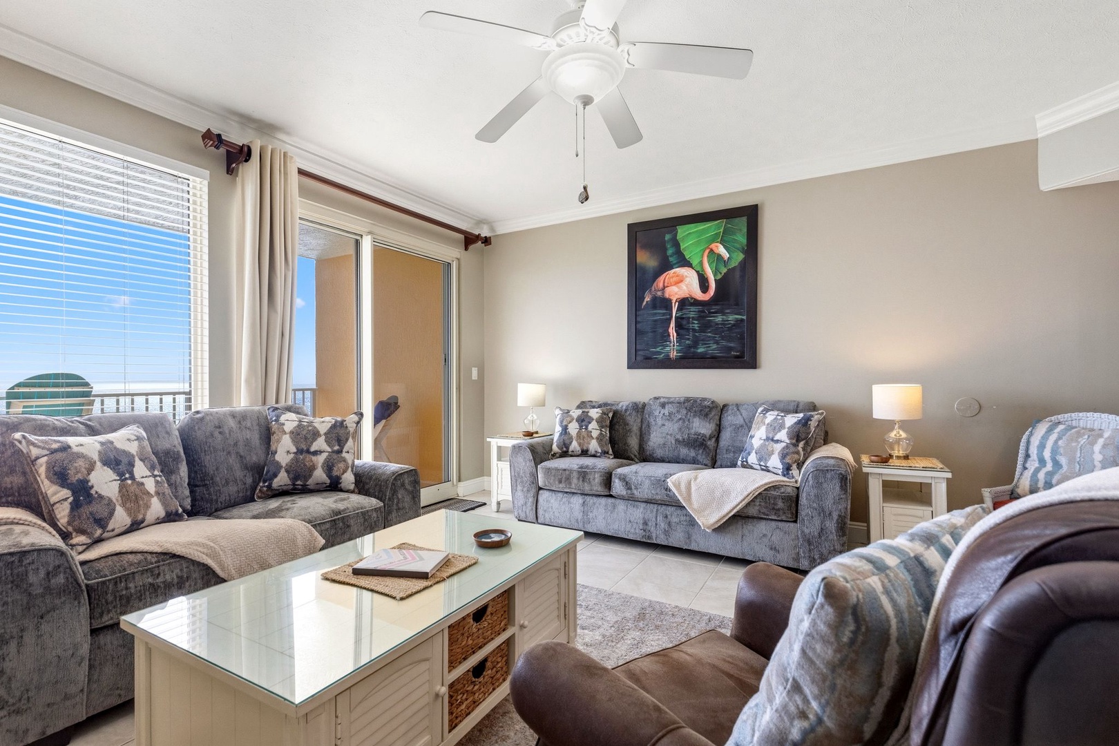 Relax in your spacious living room with plush seating, coastal artwork, and a refreshing ceiling fan overhead.