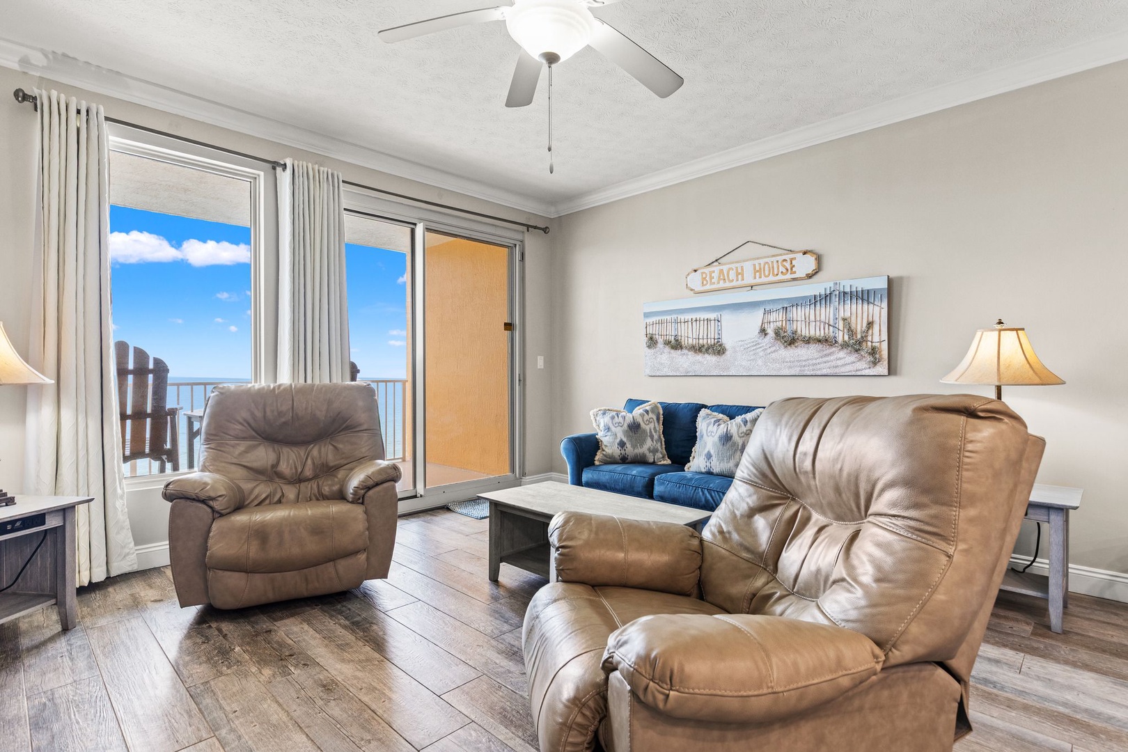 Unwind in your coastal living room where plush seating invites relaxation and ocean breezes drift through the balcony doors—your perfect beach retreat awaits.