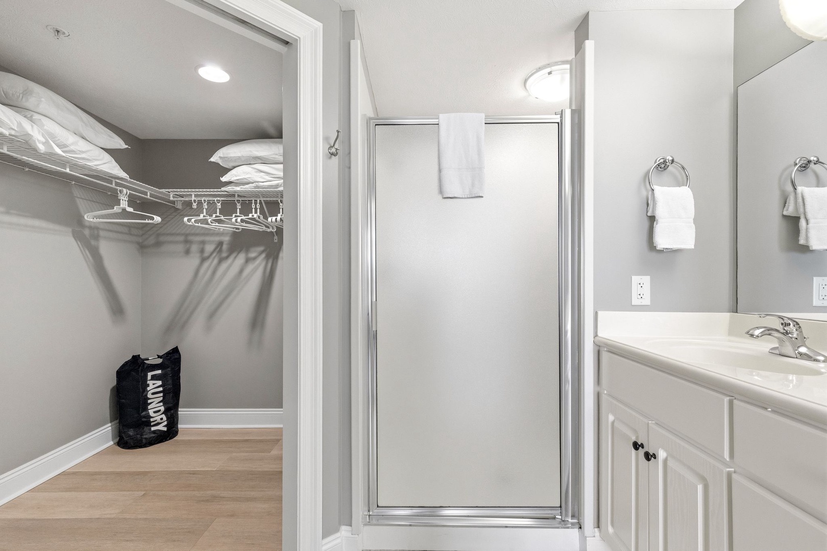 Fresh towels and a spacious walk-in closet with hangers await your arrival in this pristine, well-lit bathroom suite.