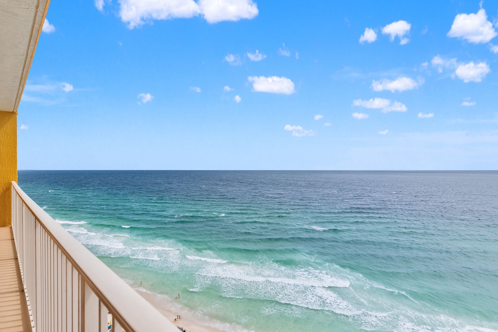 Stunning oceanfront views showcase turquoise waters meeting endless blue skies, with gentle waves rolling onto pristine sandy shores below your private balcony.