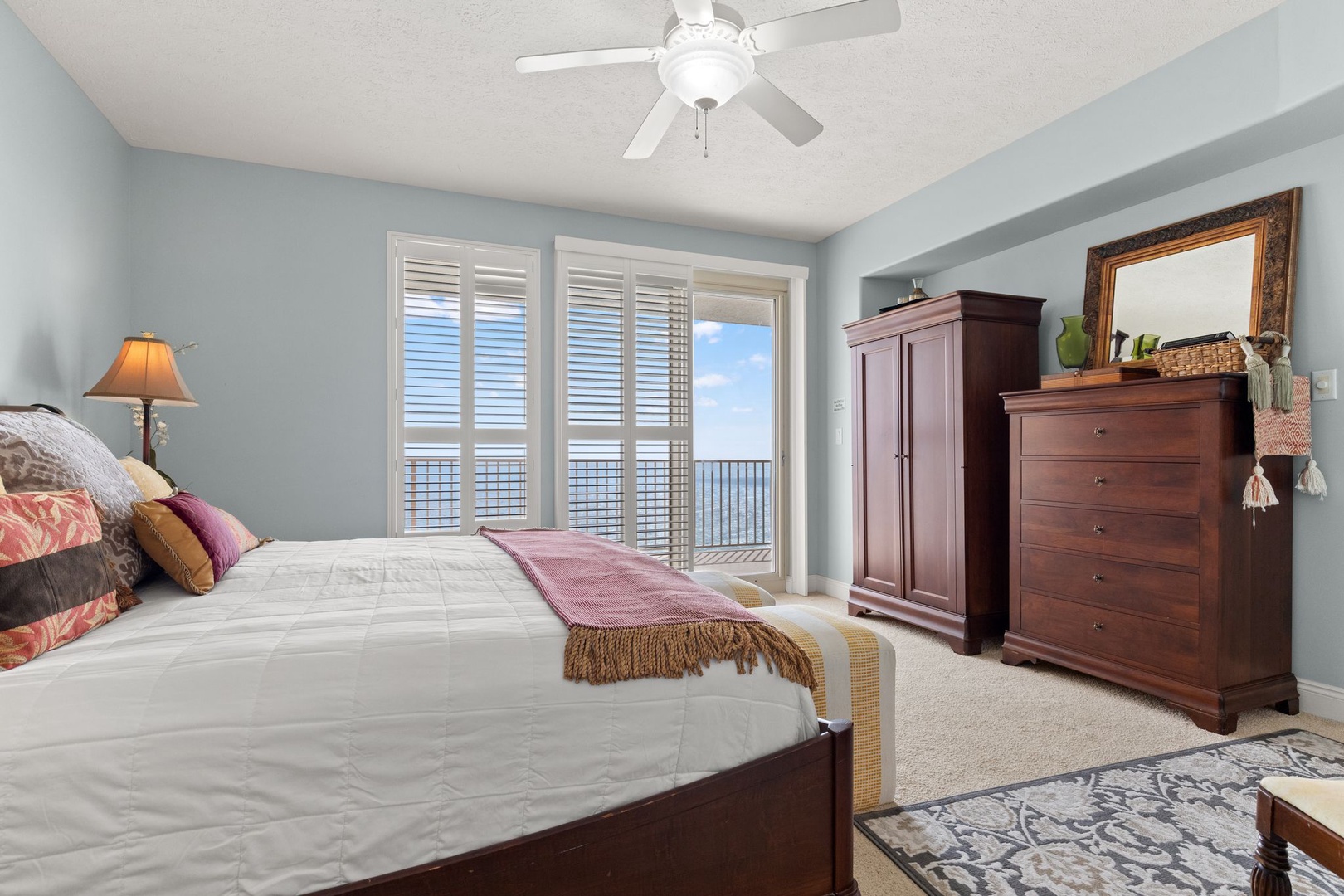 Wake up to serene coastal views from your private bedroom retreat, where soft blue walls and rich wood furnishings create a peaceful sanctuary for restful nights.
