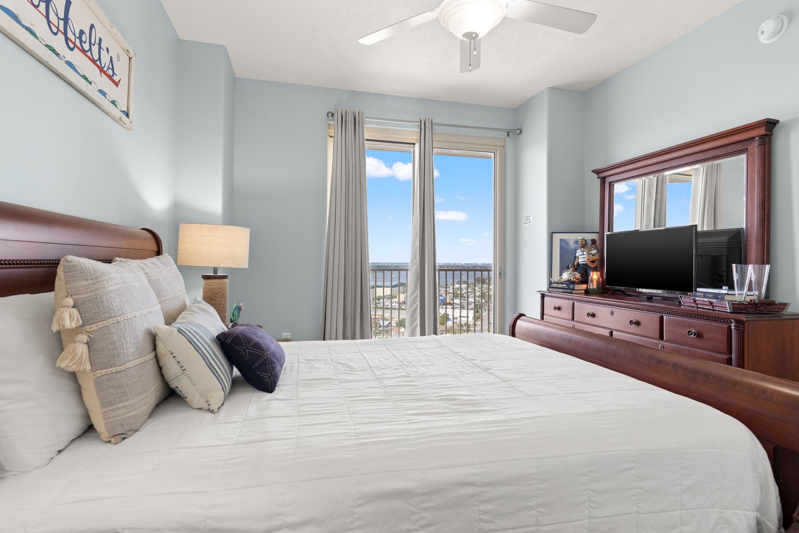 Drift off in your serene bedroom with soft coastal blues, plush bedding, and a ceiling fan overhead. Wake to sunlight and expansive views through your private balcony doors.