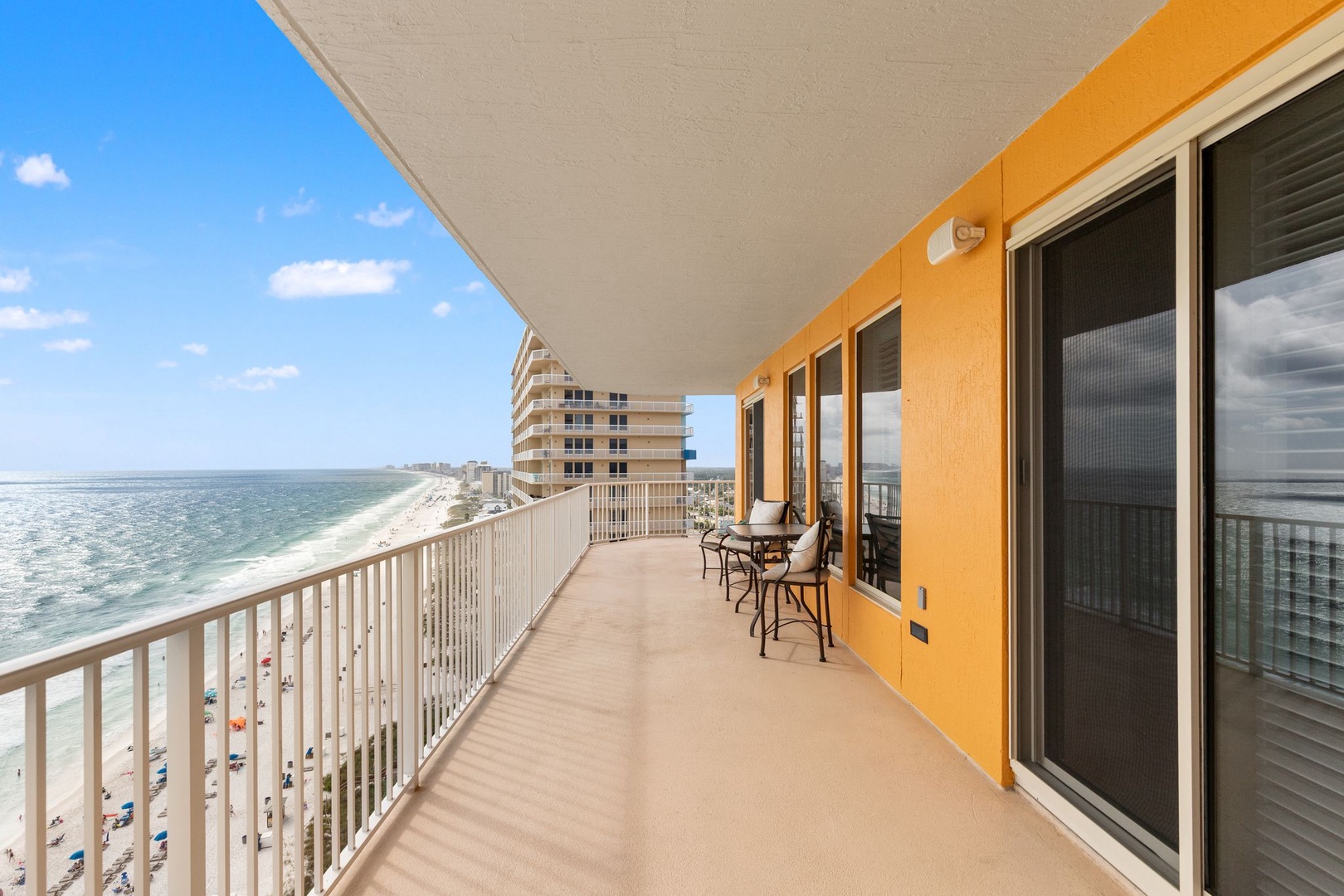 Spacious beachfront balcony with sweeping ocean and coastline views, featuring comfortable seating to enjoy sunrises, sea breezes, and the sound of waves below.