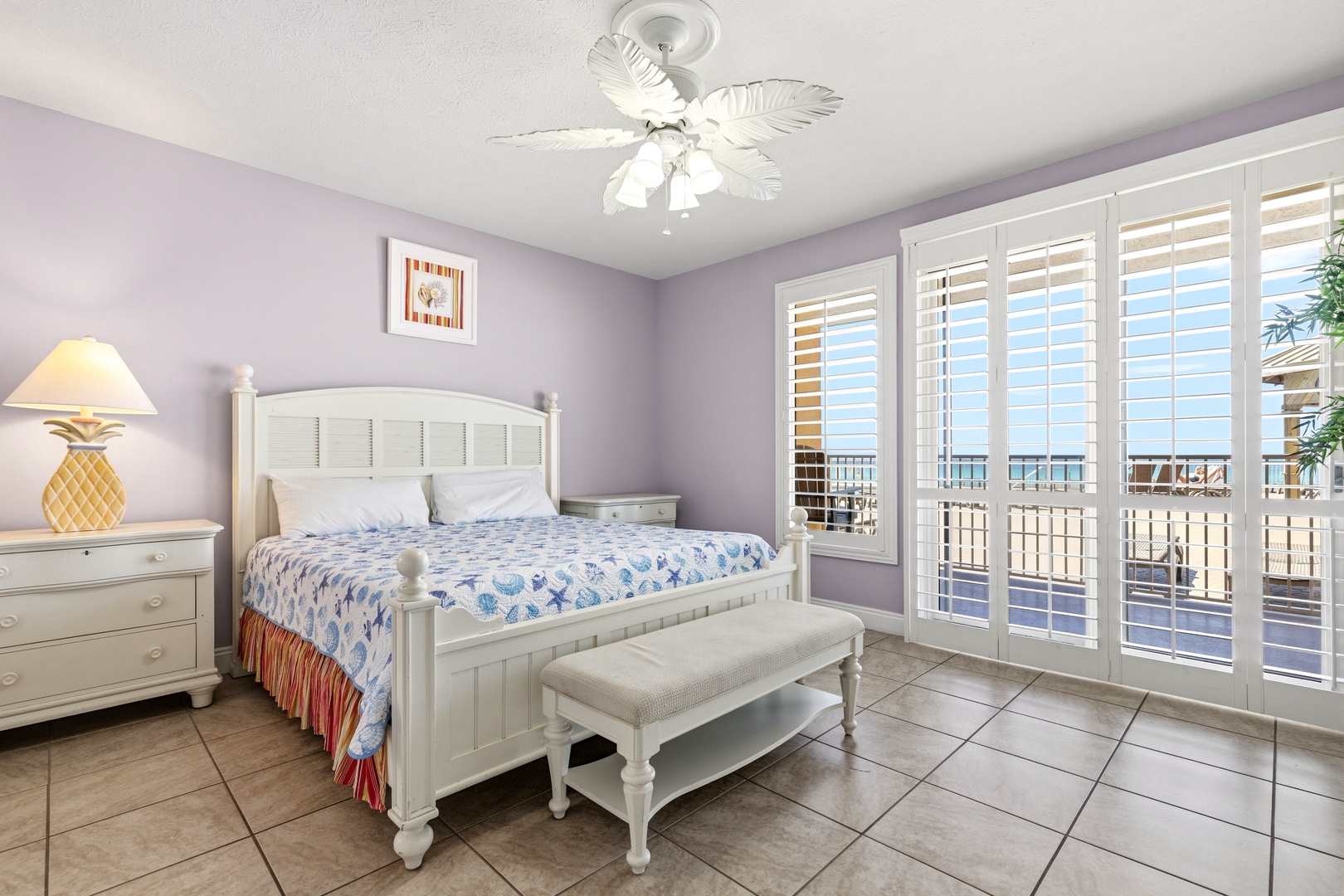 Your coastal bedroom features crisp white furnishings, soothing lavender walls, and shuttered doors opening to your private balcony.