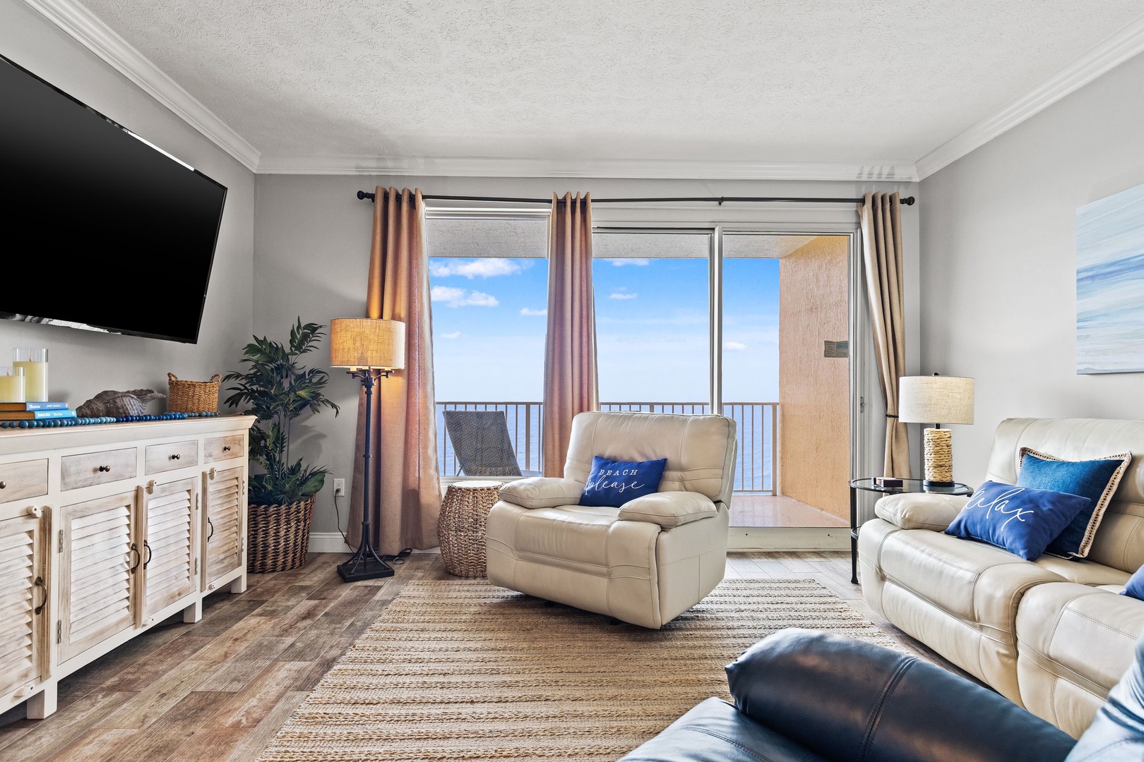 Sink into plush seating in your bright living room, where the ocean stretches endlessly beyond your private balcony and soft coastal breezes invite pure relaxation.