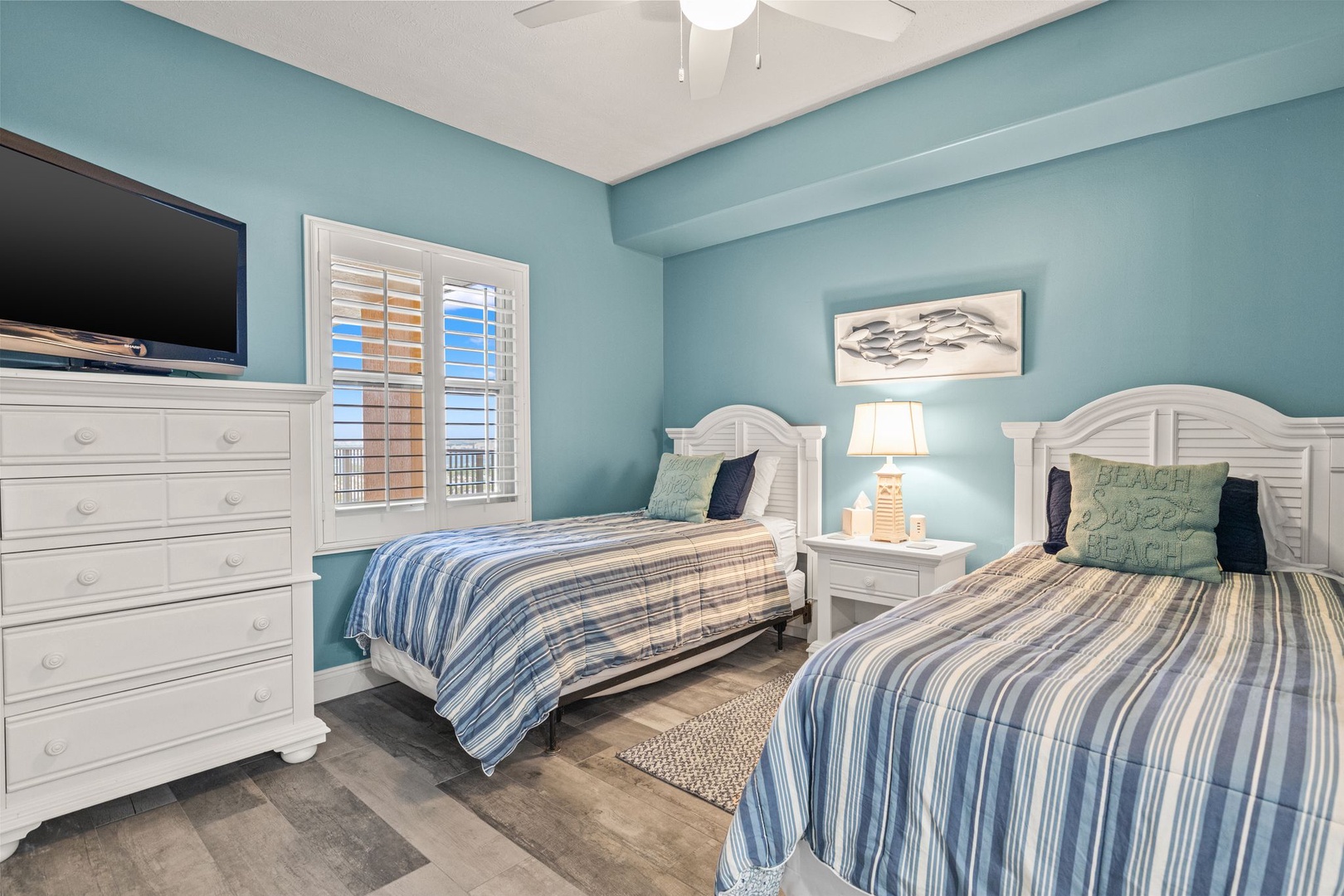 Unwind in your coastal haven with twin beds dressed in soothing blue stripes, crisp white furniture, and gentle aqua walls that echo the ocean breeze.