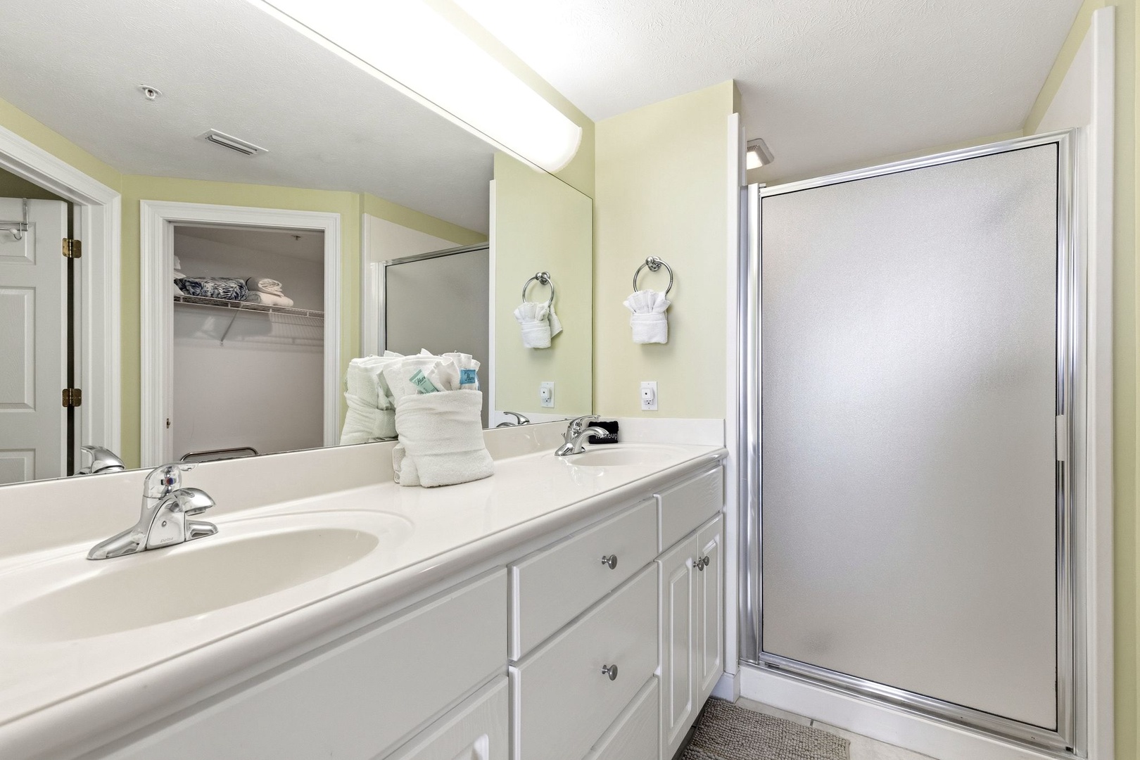 Freshen up in your bright bathroom featuring a spacious vanity, pristine shower, and thoughtful touches like fluffy towels.