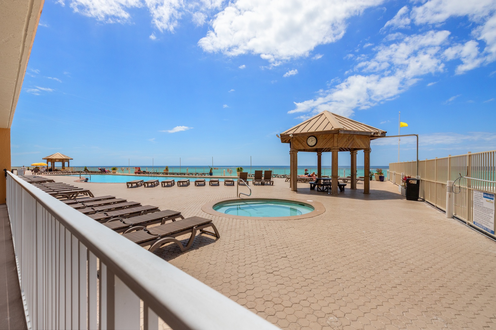 Beachfront pool deck with hot tub, loungers, and Gulf views creates the perfect coastal retreat setting.